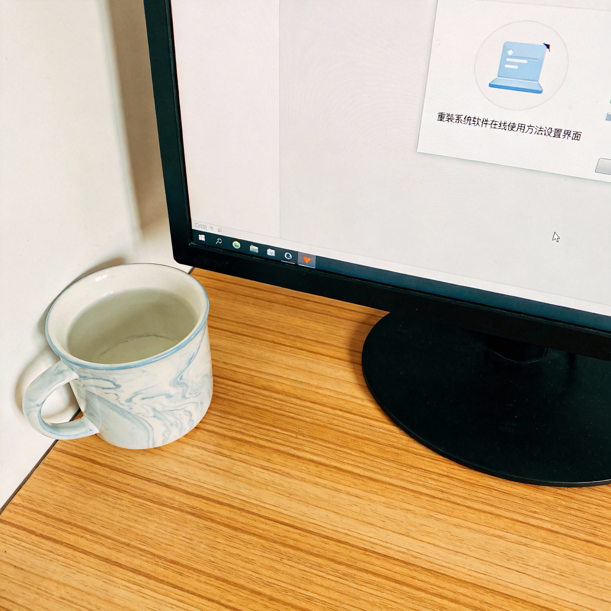 书桌上的电脑,屏幕显示重装系统软件在线使用方法设置界面,桌角放着水杯,自然光 书桌上的电脑,屏幕显示重装系统软件在线使用方法设置界面,桌角放着水杯,自然光
