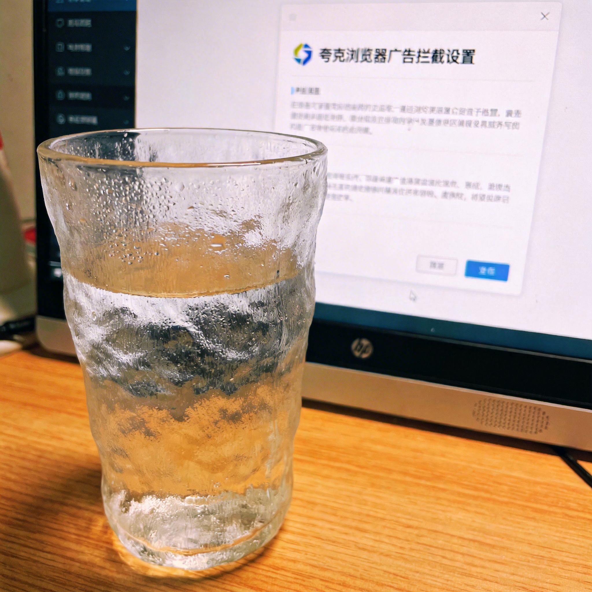 书桌上的主机，屏幕显示夸克浏览器广告拦截设置设置界面，桌角放着水杯，自然光