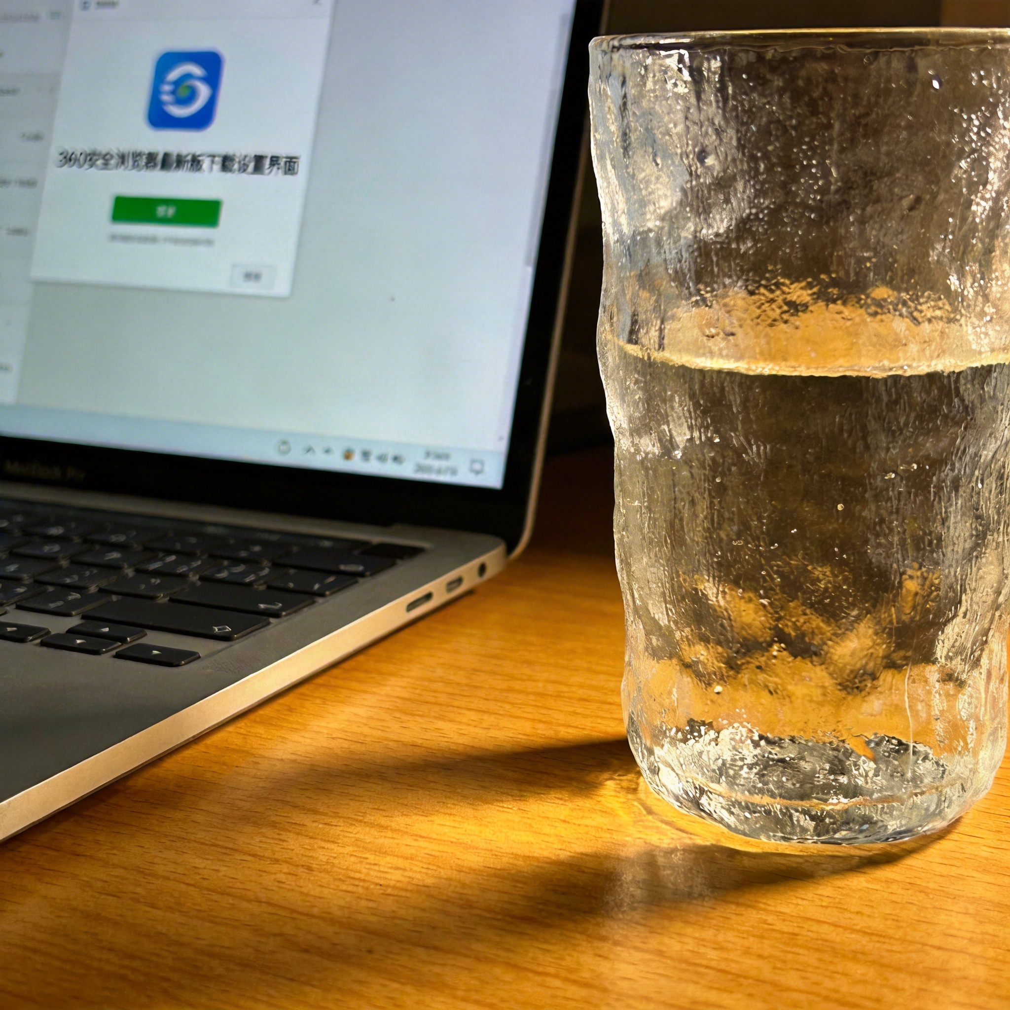 书桌上的笔记本，屏幕显示360 安全浏览器最新版下载设置界面，桌角放着水杯，自然光