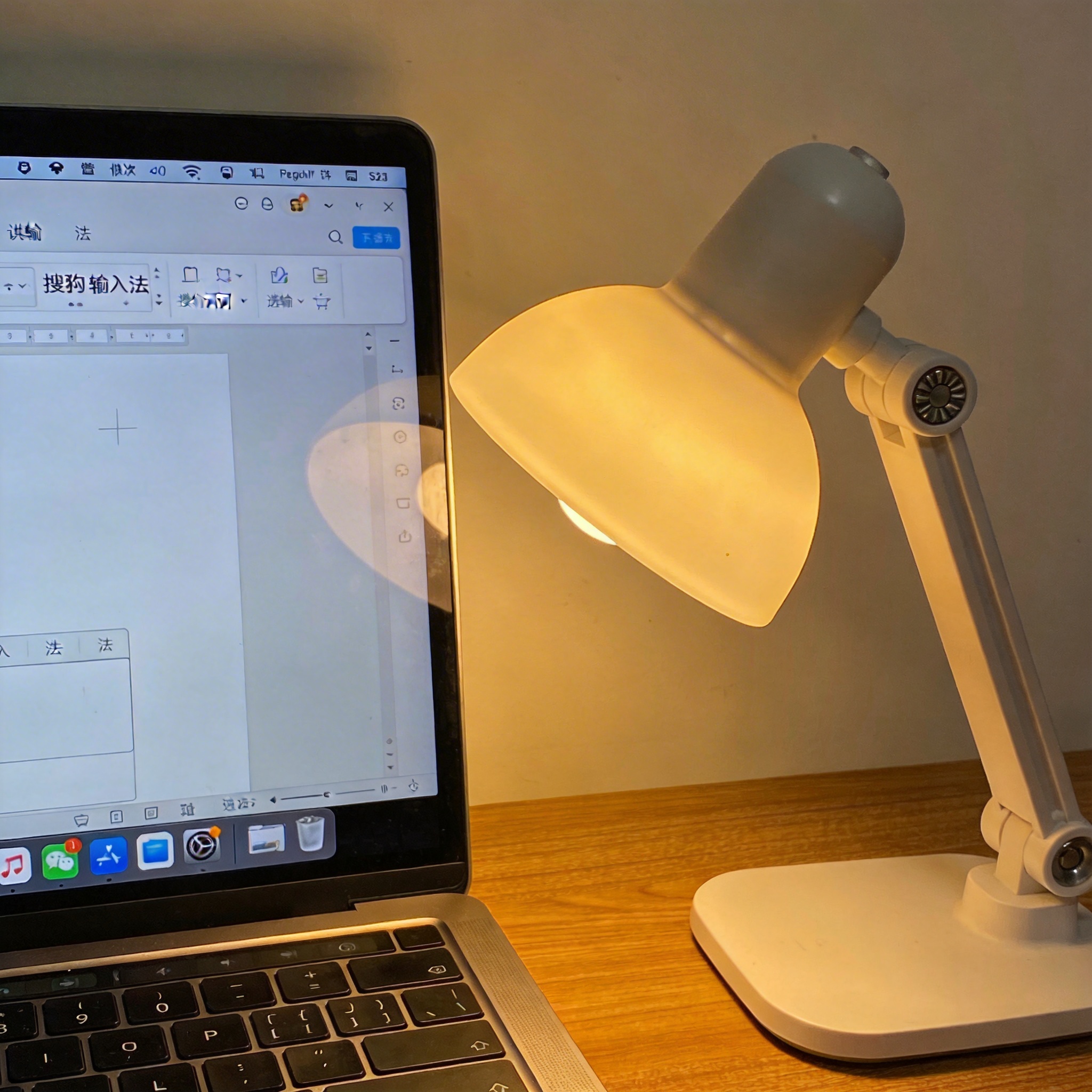 电脑桌上的电脑，屏幕显示搜狗输入法界面，旁边放着台灯