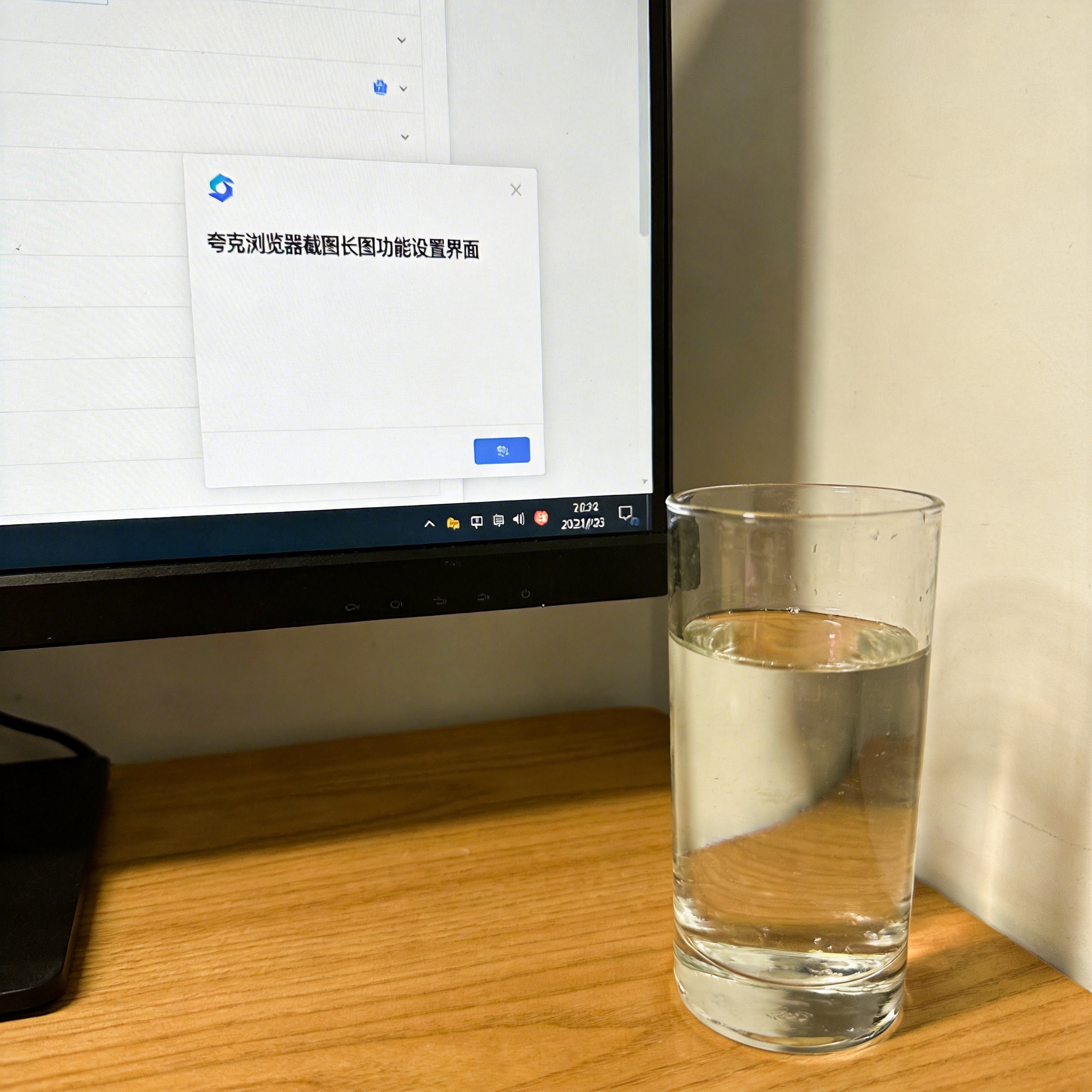 书桌上的主机，屏幕显示夸克浏览器截图长图功能设置界面，桌角放着水杯，自然光