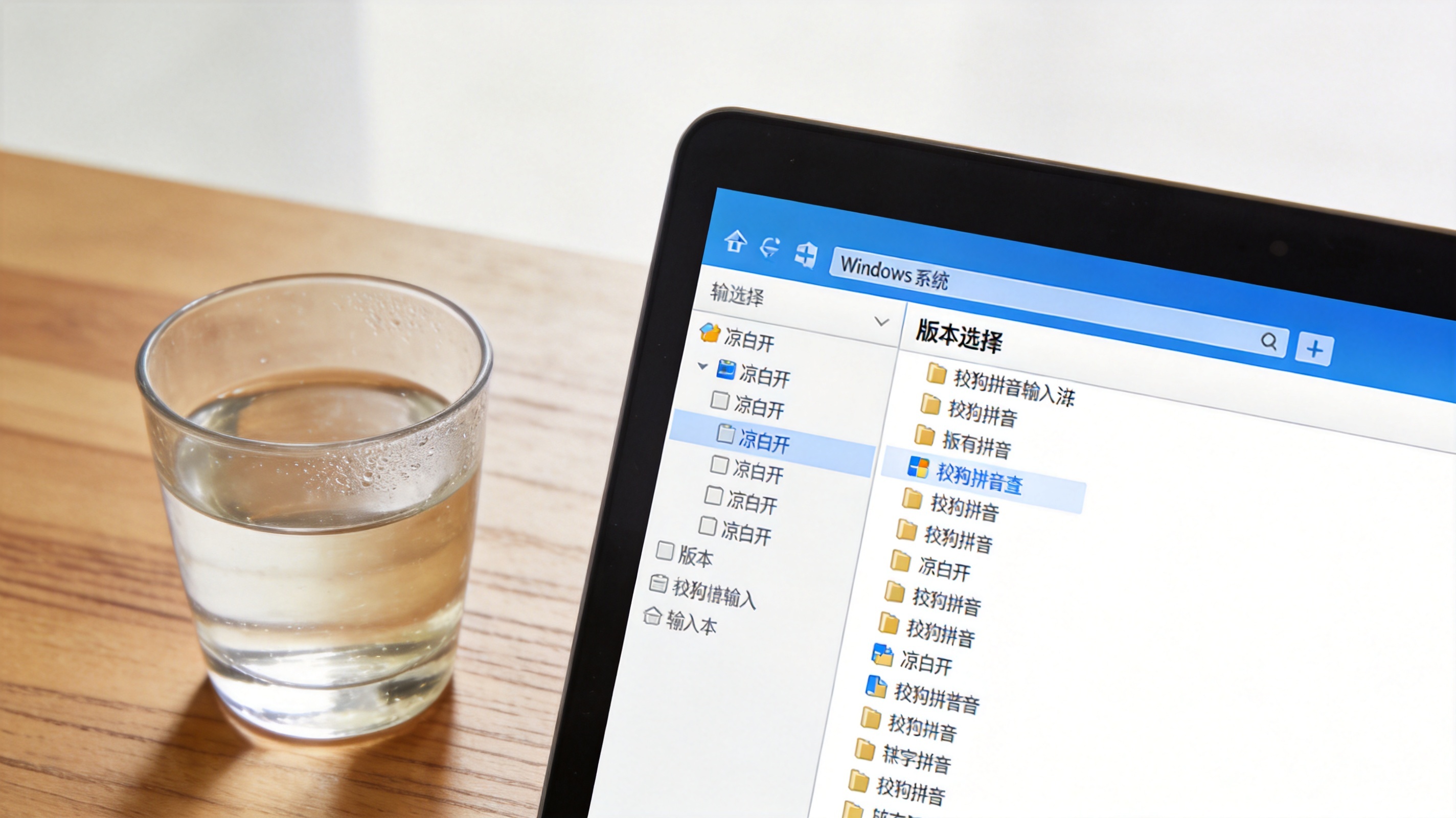 电脑桌面，屏幕显示Windows系统下的搜狗拼音输入法版本选择界面，旁边放着半杯凉白开，室内自然光