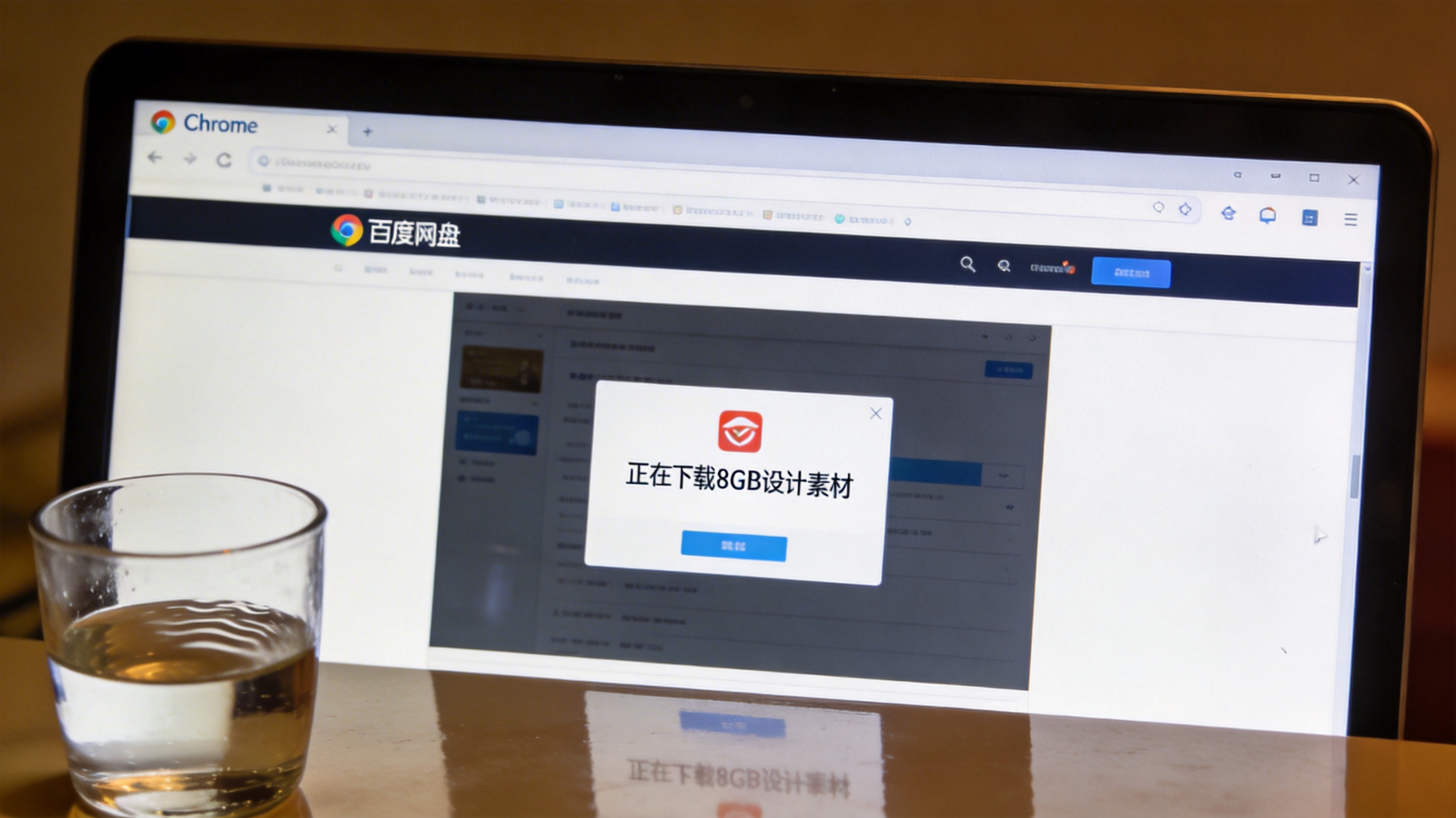 电脑桌面的Chrome浏览器，屏幕显示百度网盘网页界面，正在下载8GB设计素材，旁边放着半杯温水，屏幕光照亮桌面