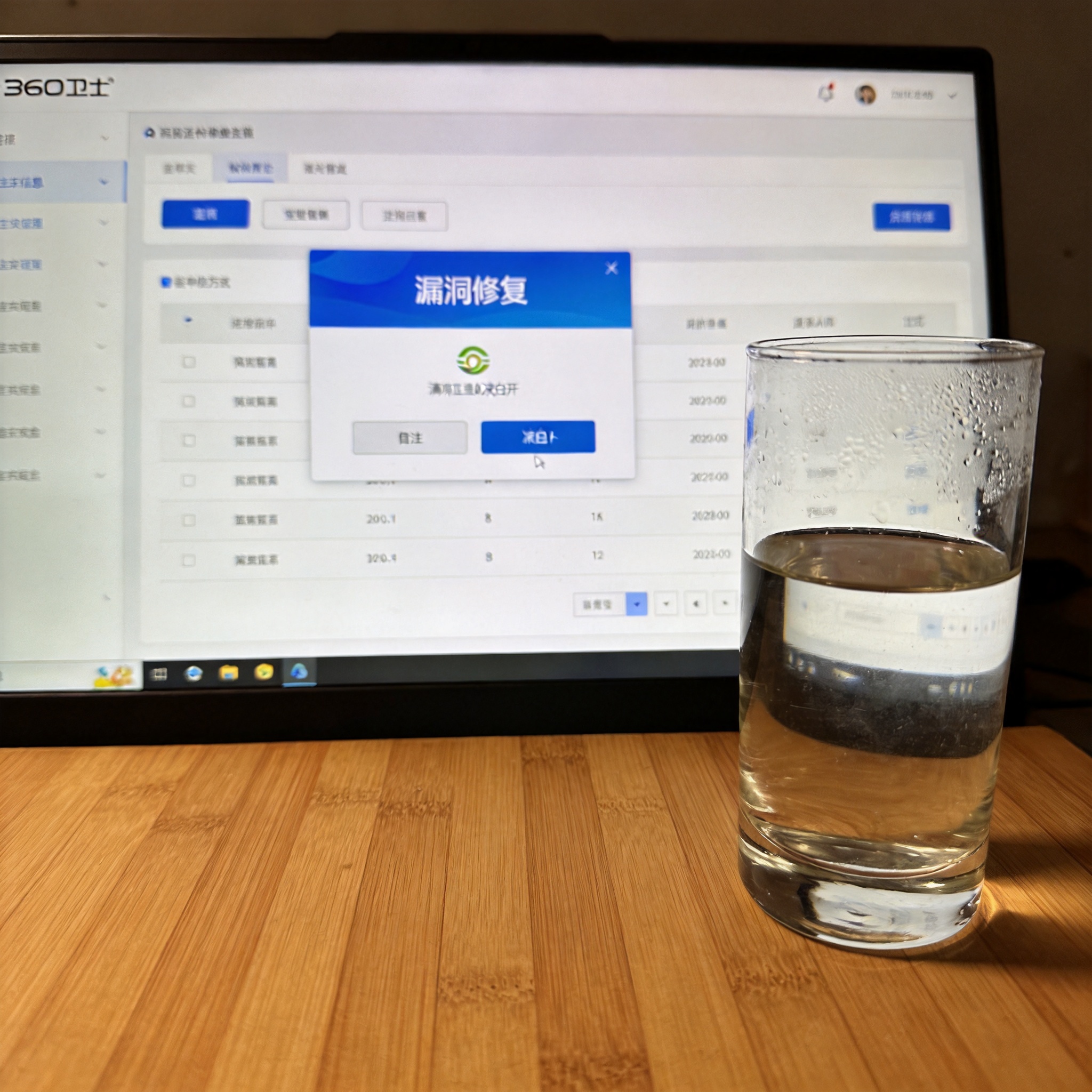 电脑桌的电脑屏幕显示360卫士主界面，“漏洞修复”板块在显眼位置，旁边放着半杯凉白开，室内自然光