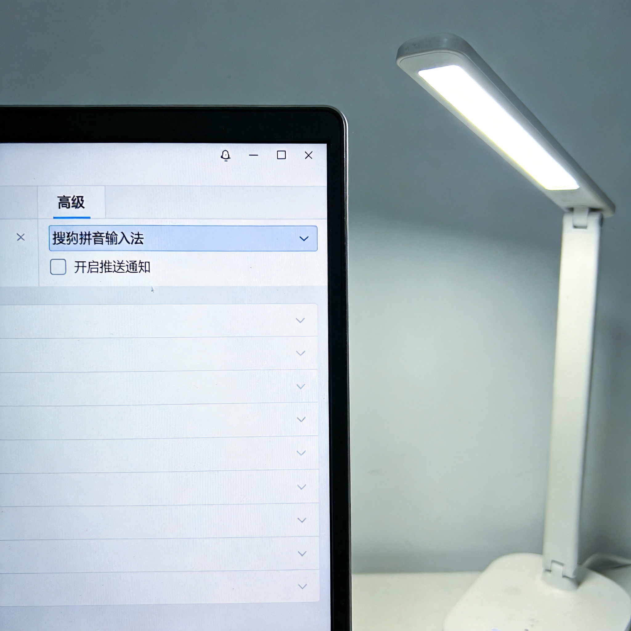 电脑屏幕显示搜狗拼音输入法设置界面，打开“高级”选项卡，“开启推送通知”勾选框已取消，旁边有台发出冷光的桌面台灯