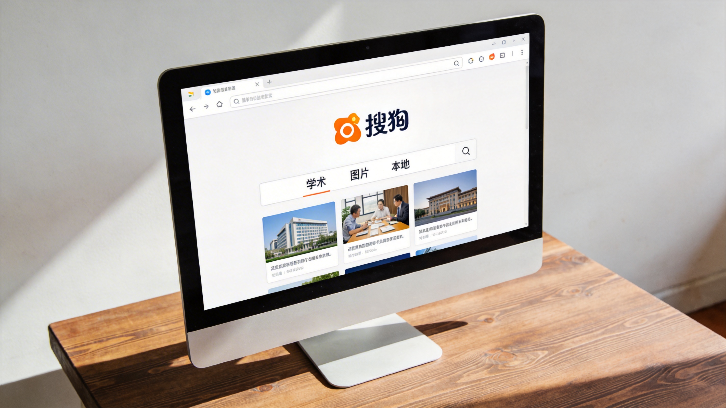 电脑放在桌面上，屏幕显示搜狗搜索首页，首页显眼位置排列着学术、图片、本地几个搜索分类选项，室内自然光