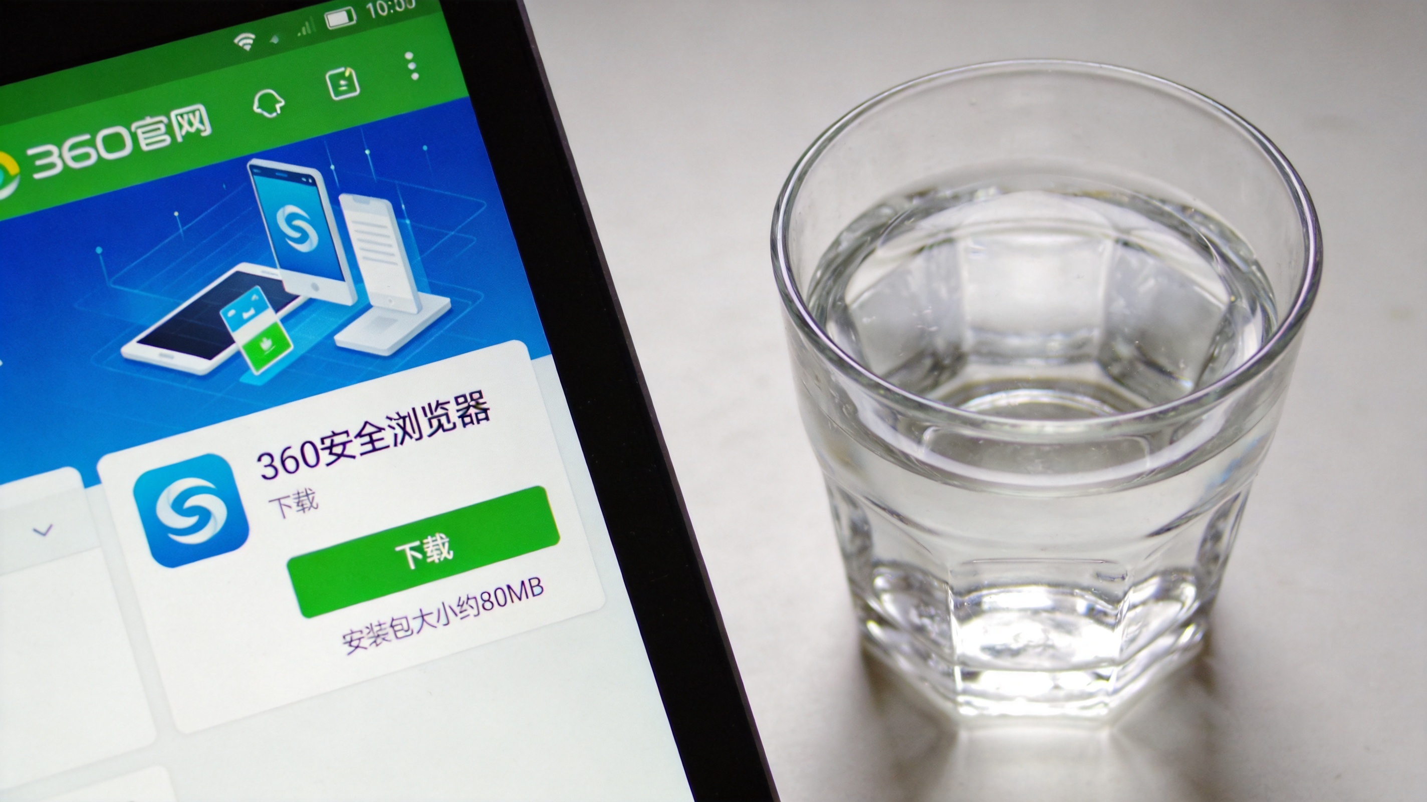 电脑屏幕显示360官网产品板块页面，360安全浏览器的下载按钮清晰可见，下方标注安装包大小约80MB，旁边放着半杯白水