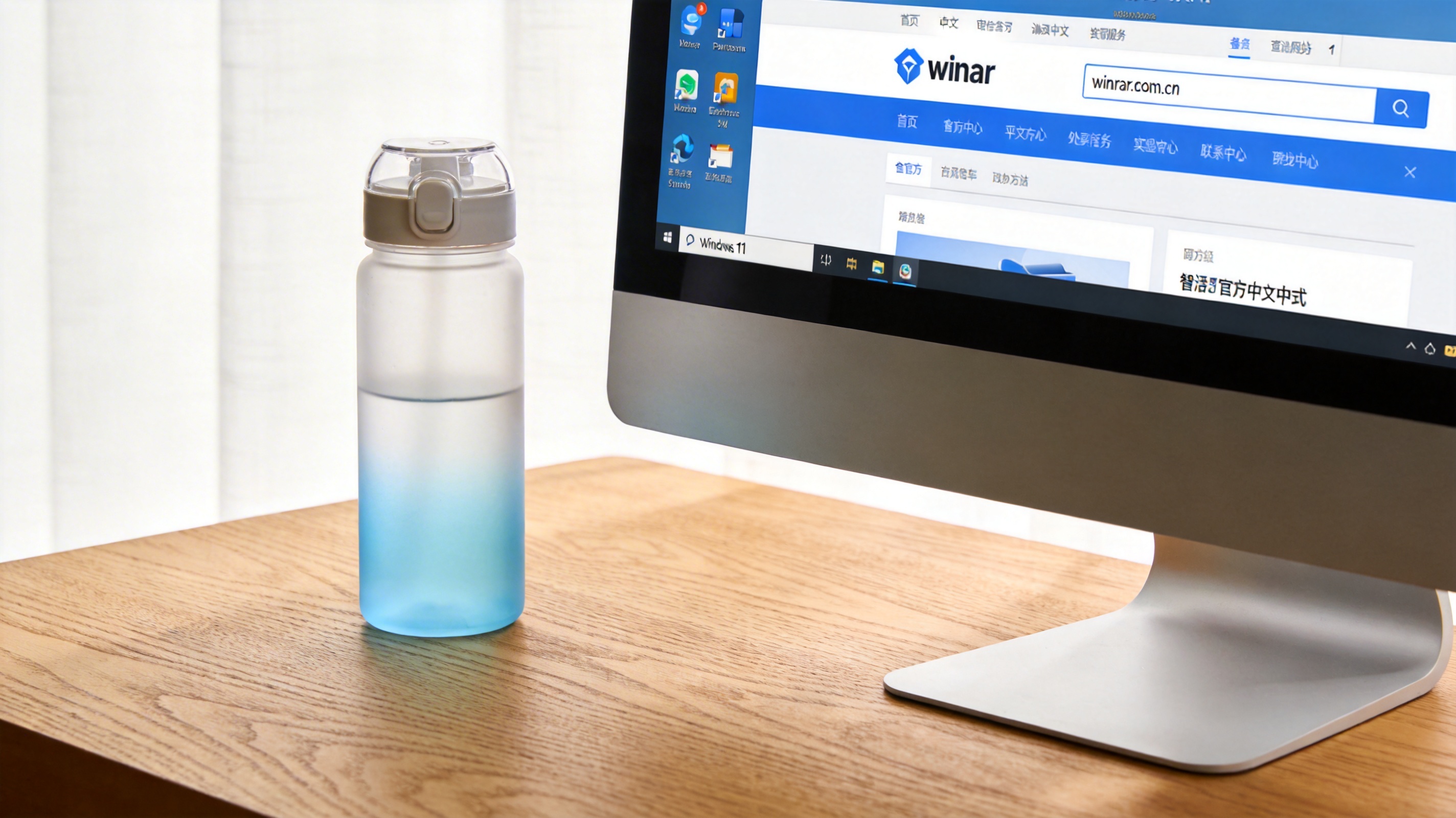 电脑桌的Windows11系统电脑，屏幕显示winrar官方中文网站页面，域名栏显示winrar.com.cn，旁边放着半透明水杯，室内自然光