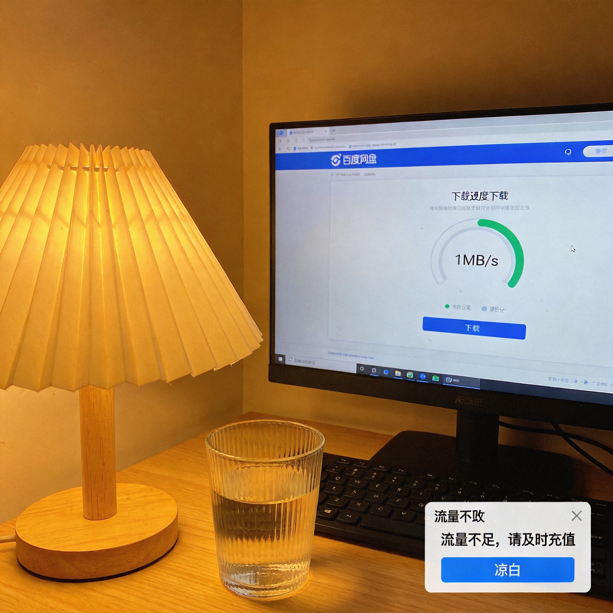 电脑屏幕显示百度网盘下载界面，下载速度显示1MB/s，桌面右下角弹出流量不足提示框，旁边放着半杯凉白开，台灯暖光