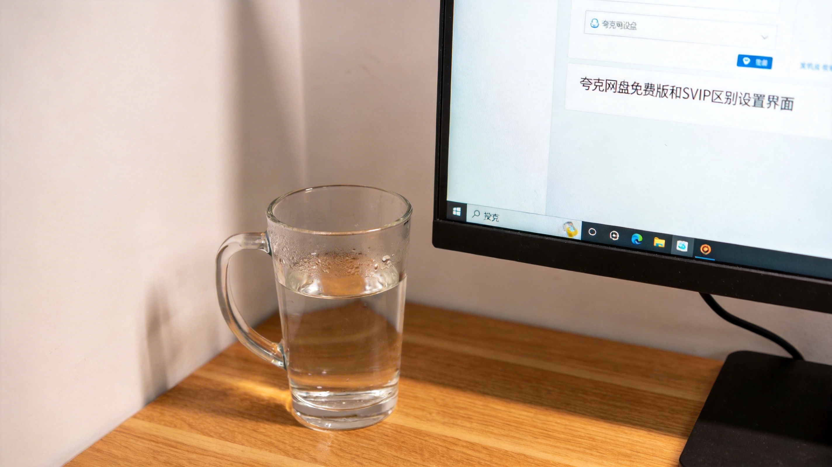 书桌上的主机，屏幕显示夸克网盘免费版和 SVIP 区别设置界面，桌角放着水杯，自然光