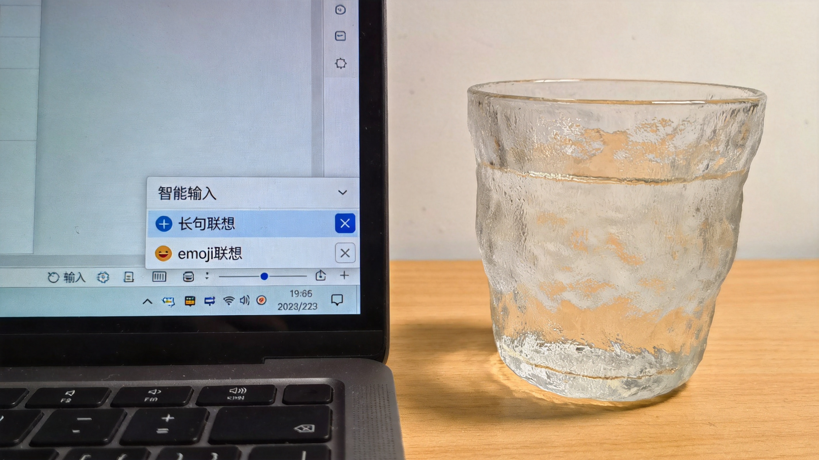 电脑桌面，屏幕显示搜狗拼音输入法的输入设置界面，智能输入选项下的长句联想、emoji联想处于关闭状态，桌面放着半杯温水，室内自然光