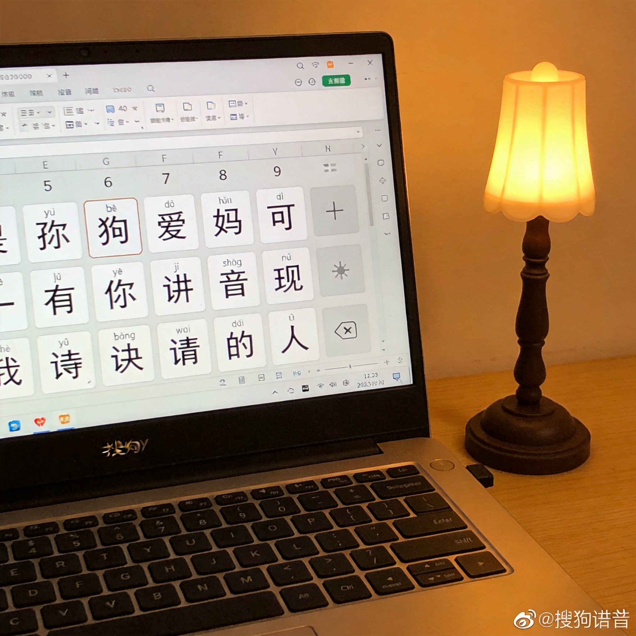 桌面的电脑屏幕显示搜狗拼音输入界面，候选词栏是大号字体，旁边摆着一盏小台灯，台灯暖光