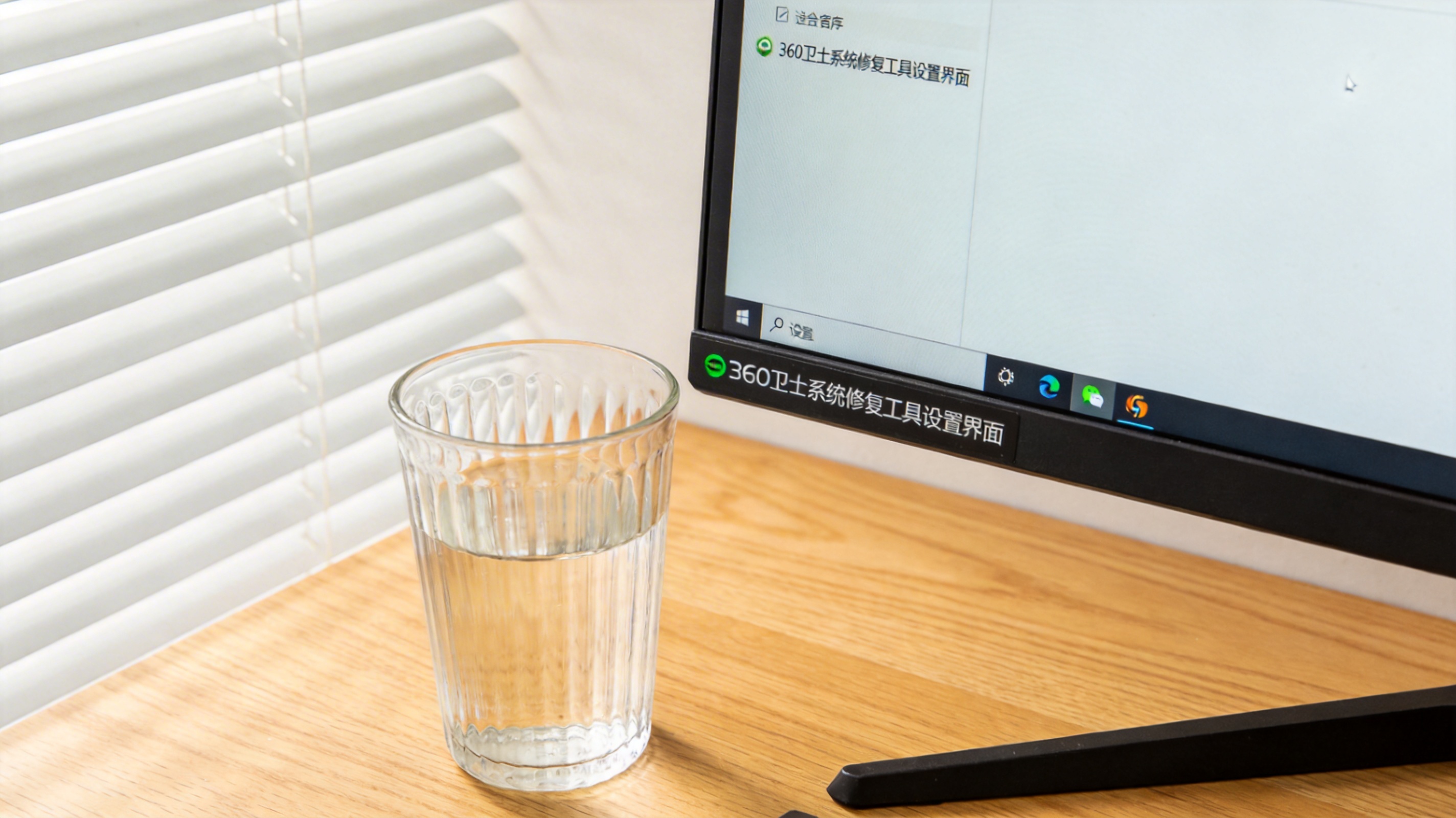 书桌上的主机，屏幕显示360 卫士系统修复工具设置界面，桌角放着水杯，自然光