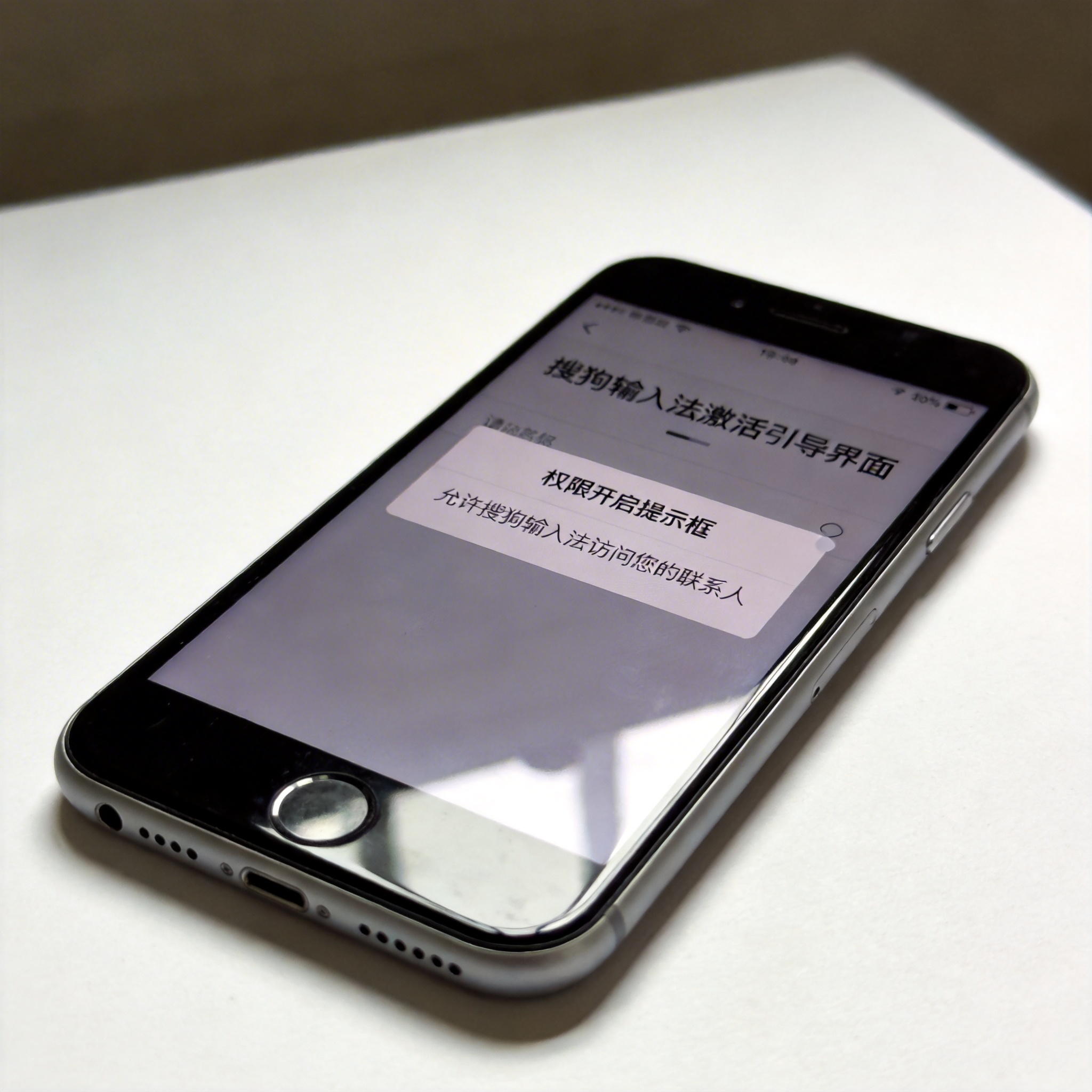 桌面放着的智能手机，屏幕显示搜狗输入法激活引导界面，下方弹出权限开启提示框，室内自然光