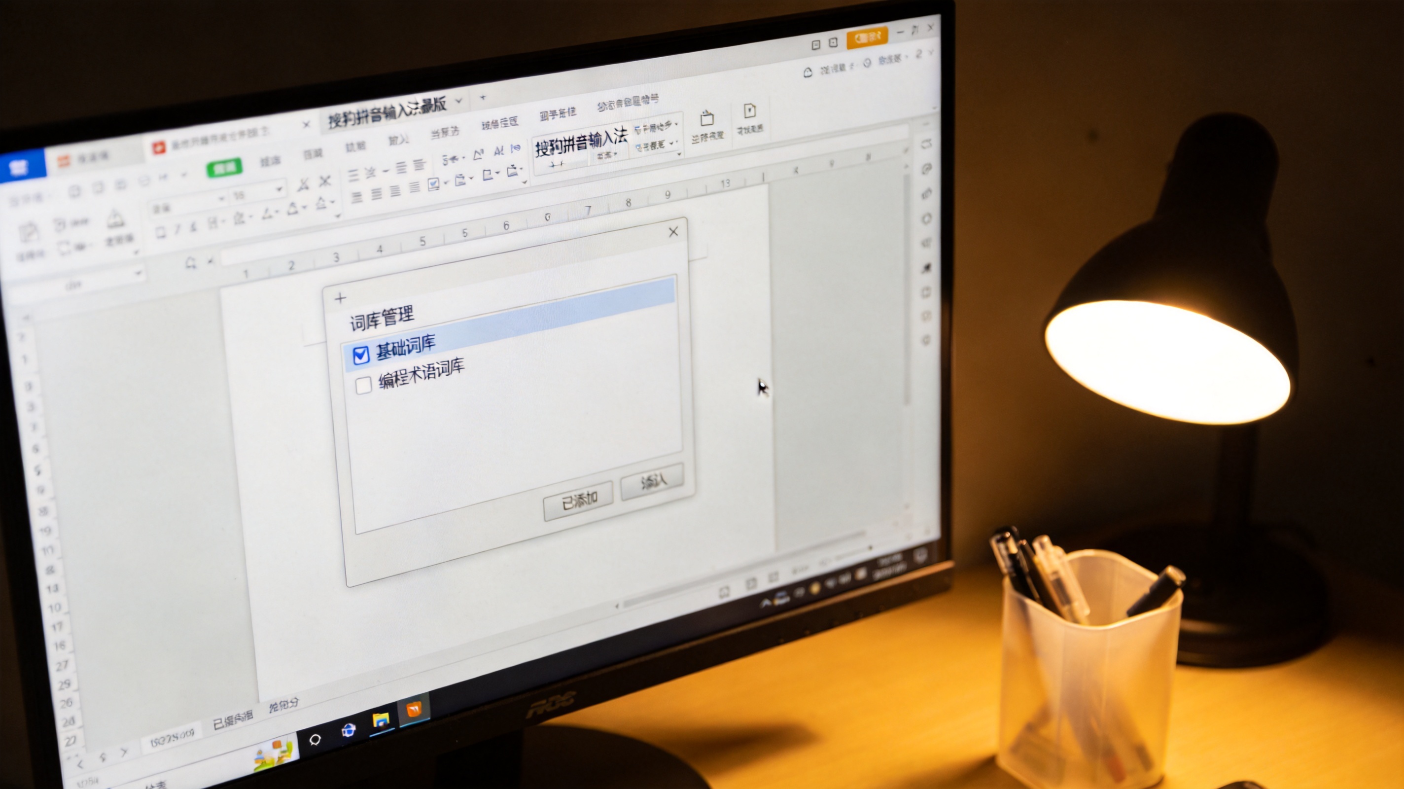 电脑屏幕显示搜狗拼音输入法最新版的词库管理面板，已勾选基础词库，还添加了编程术语词库，桌面角落有个塑料笔筒，台灯暖光