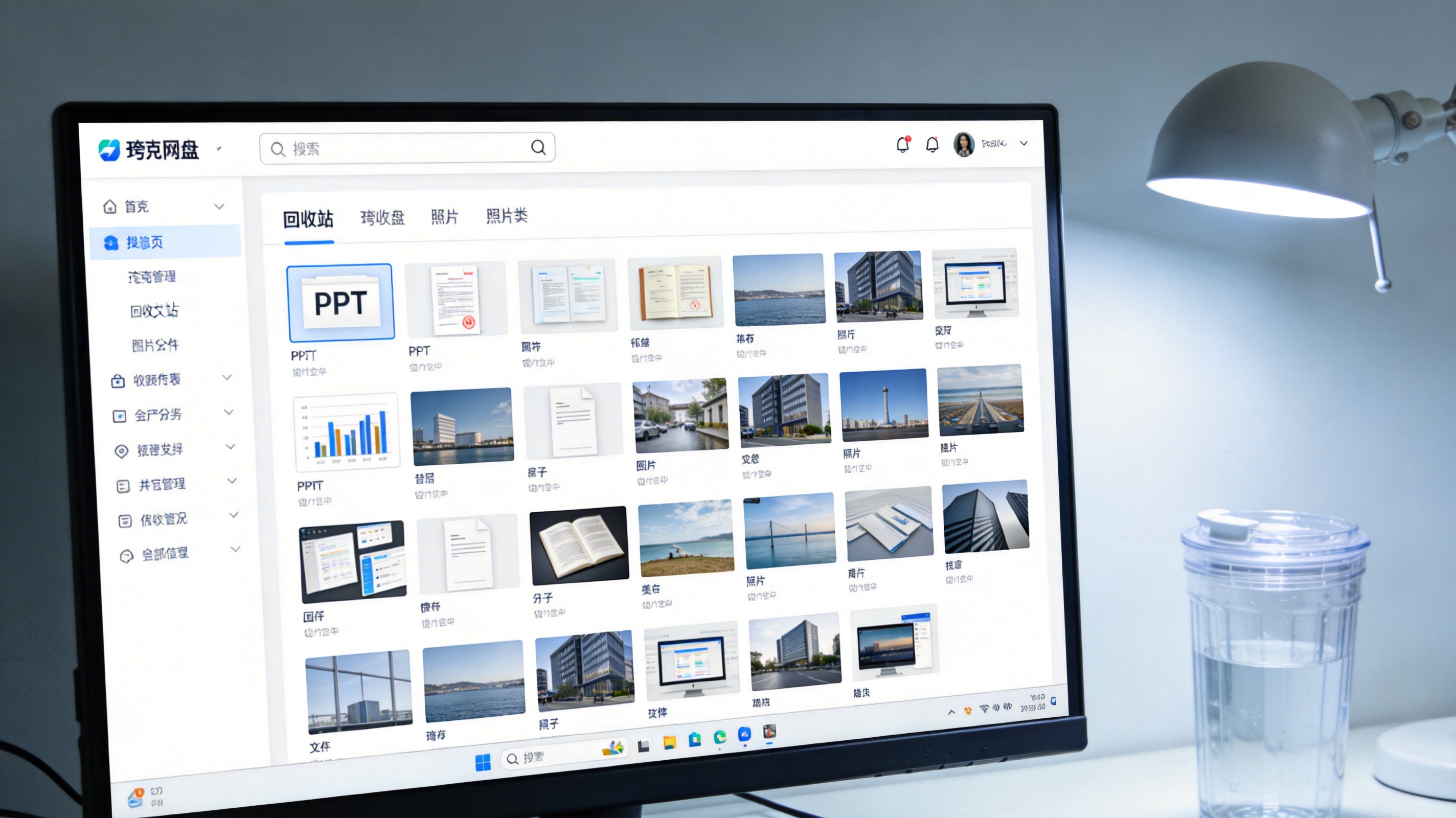 电脑屏幕显示夸克网盘回收站界面，列表里有PPT、照片类文件，顶部搜索框空白，旁边桌面放着塑料水杯，台灯冷光