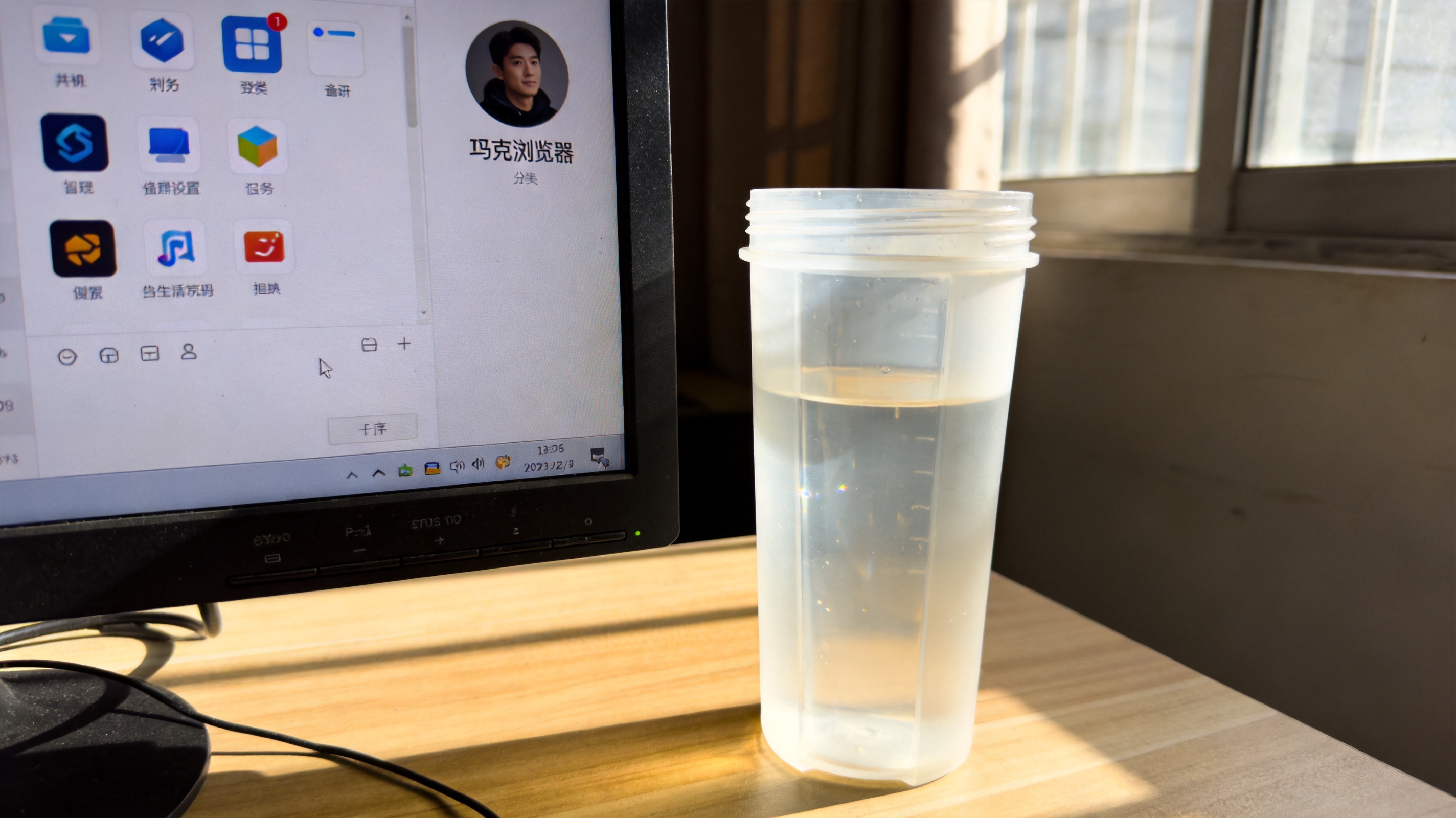 电脑桌面，屏幕显示夸克浏览器主界面，右上角显示头像图标，旁边放着半透明塑料水杯，室内自然光