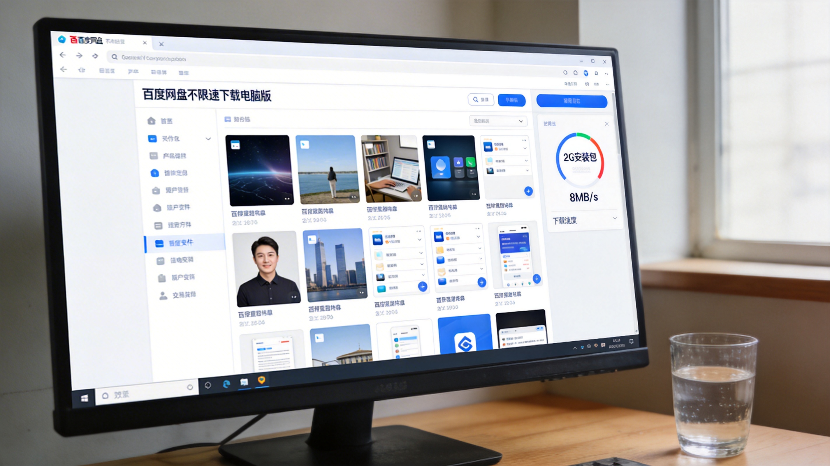 电脑桌面，屏幕显示百度网盘不限速下载电脑版的文件列表界面，右侧显示2G安装包的下载速度为8MB/s，桌面角落放着半杯水，室内自然光