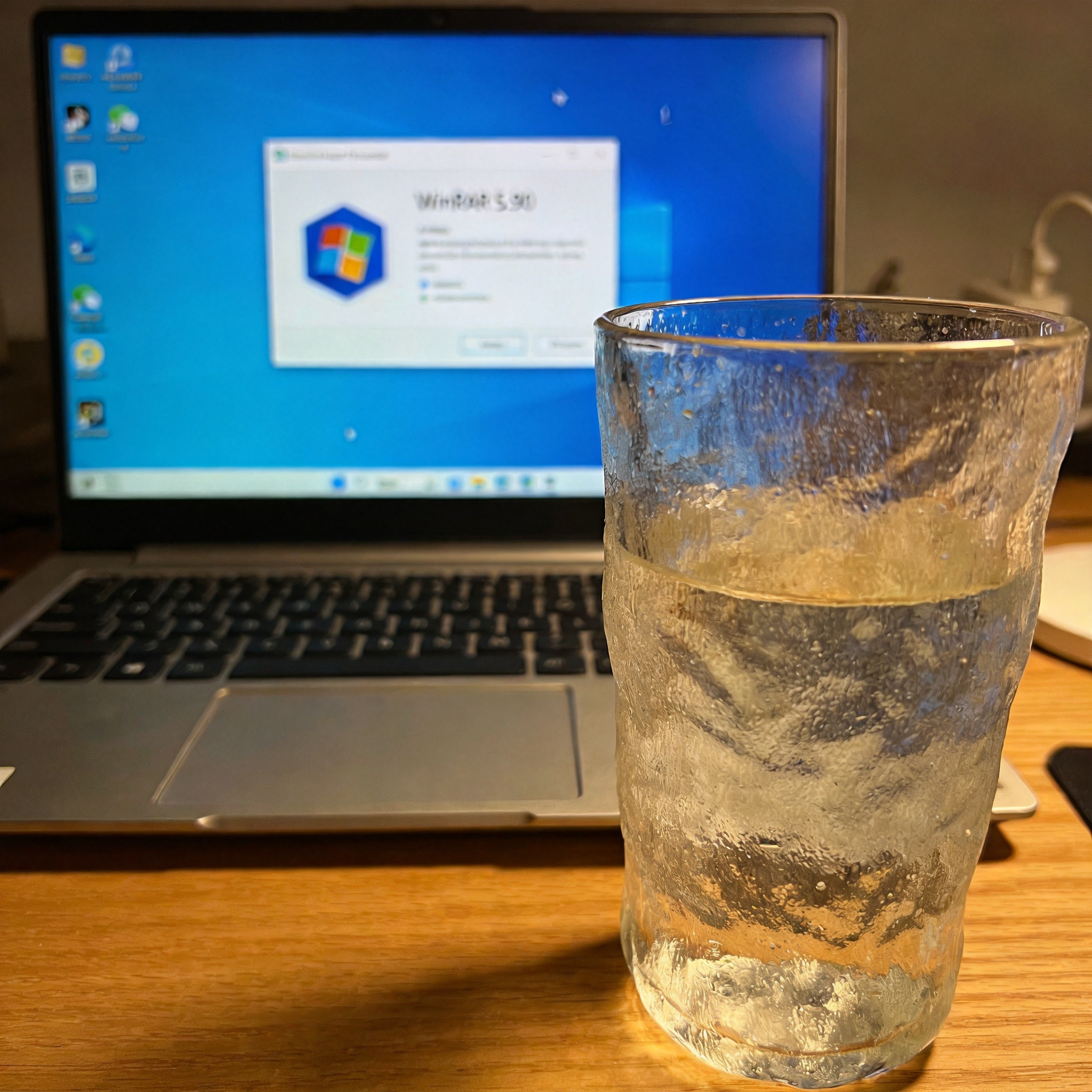 电脑桌的Windows11系统电脑，屏幕显示WinRAR 5.90版本的解压界面，桌面放着半杯温水，室内自然光
