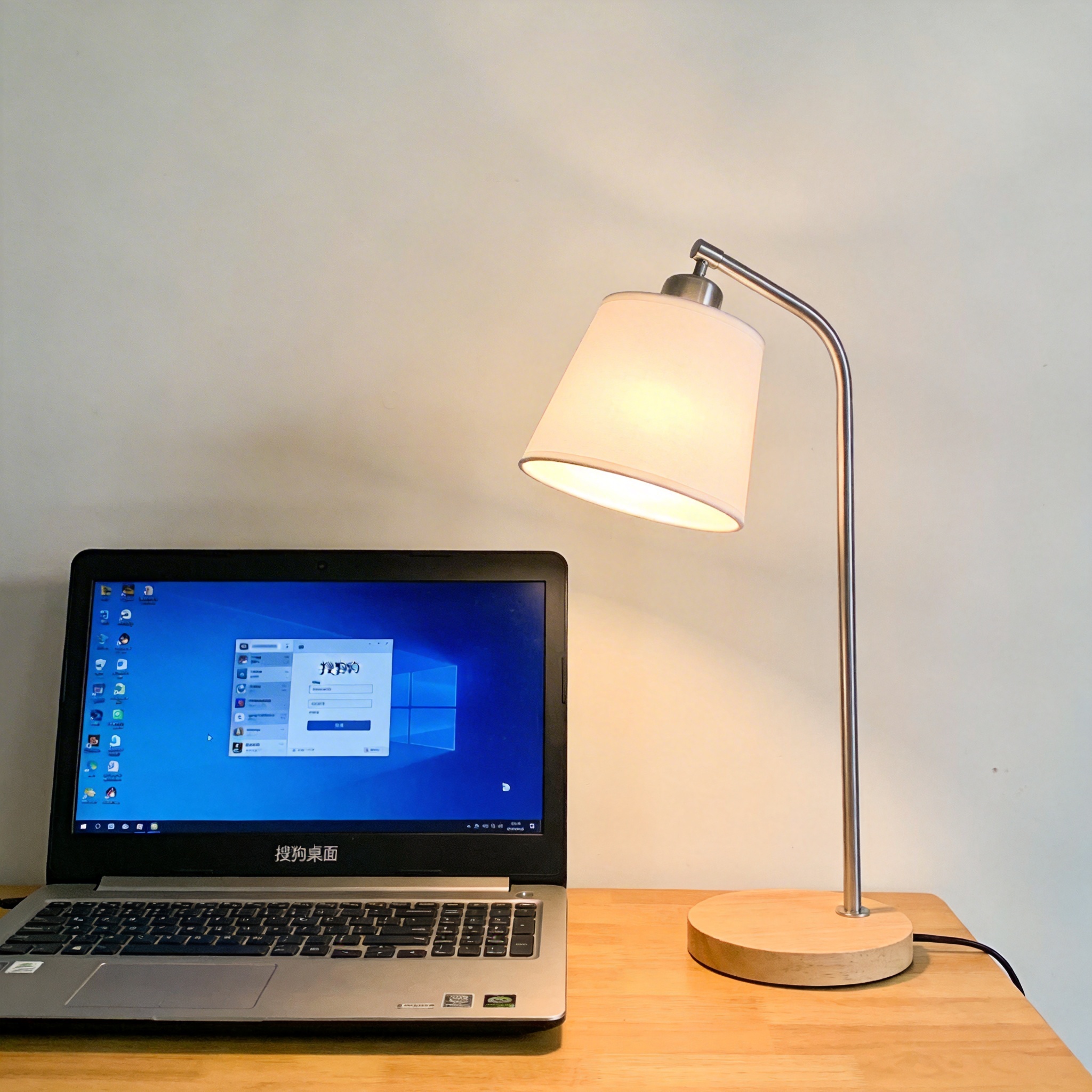 电脑桌上的电脑，屏幕显示搜狗桌面，旁边放着台灯