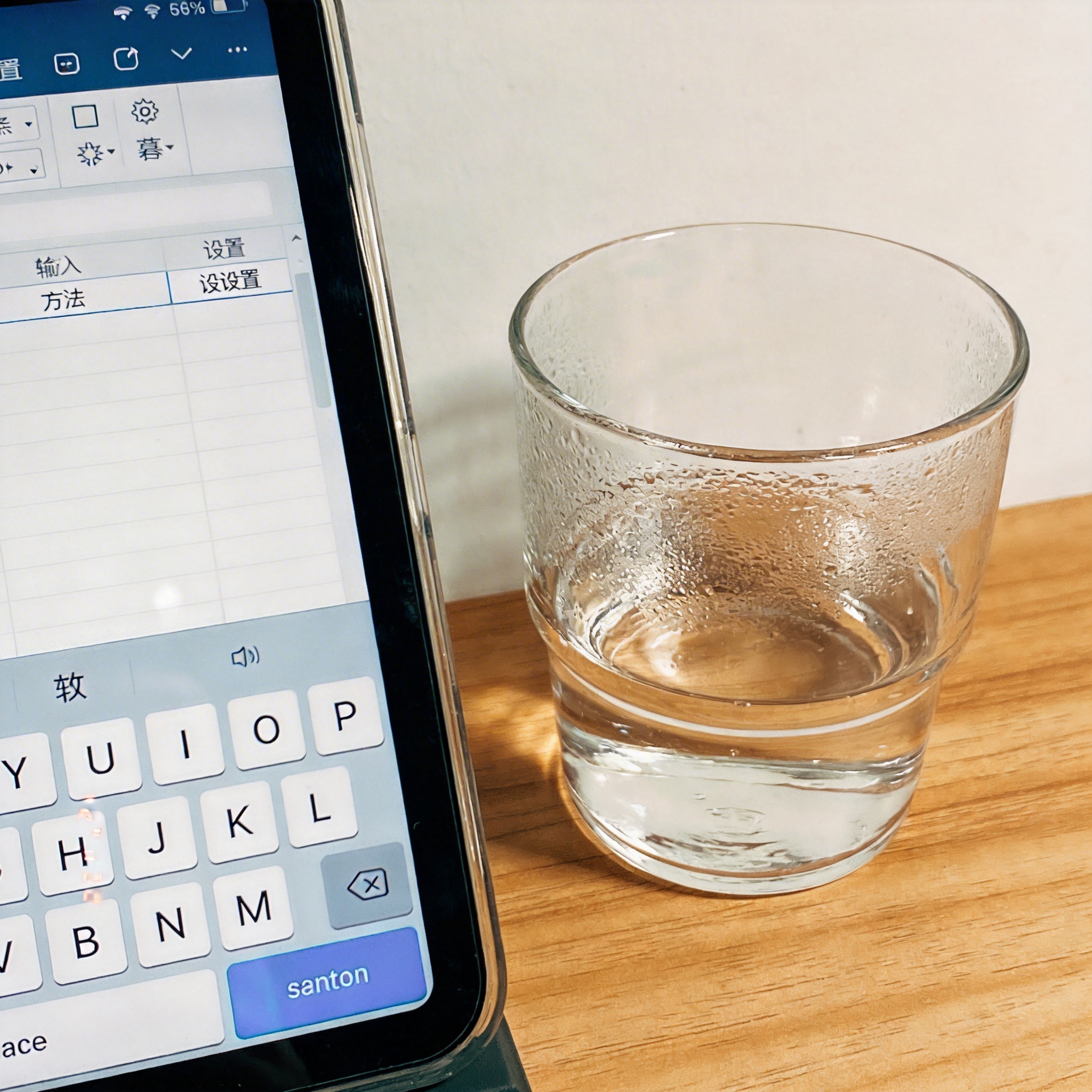 书桌上的屏幕，屏幕显示输入法设置界面，桌角放着水杯，自然光
