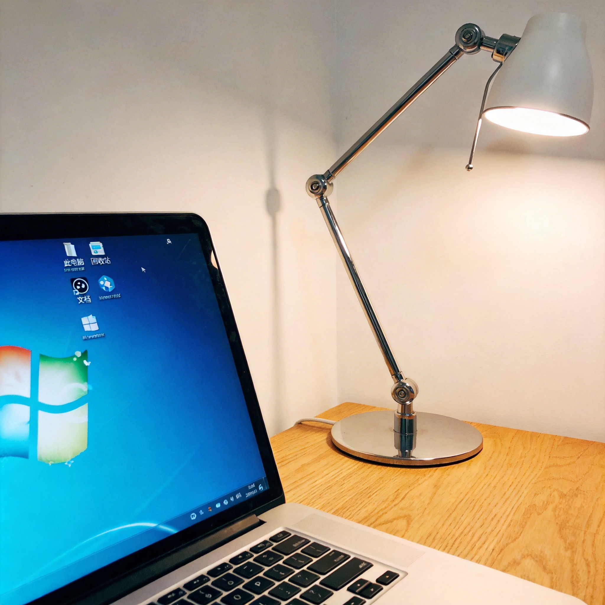 电脑桌上的电脑，屏幕显示Windows桌面，旁边放着台灯