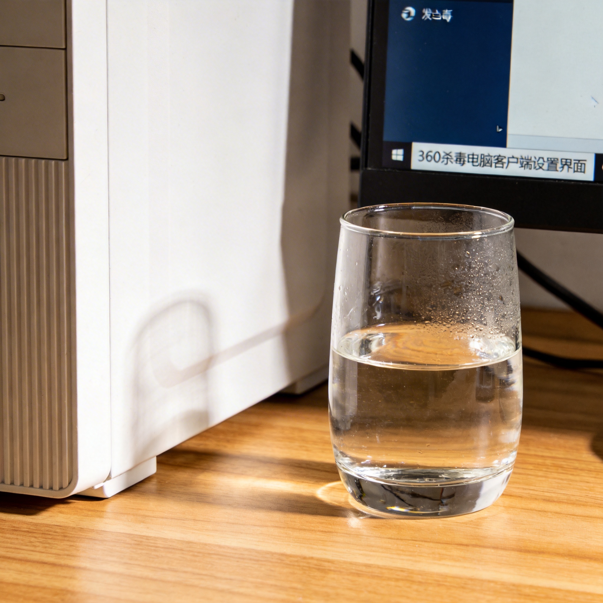 书桌上的主机，屏幕显示360 杀毒电脑客户端设置界面，桌角放着水杯，自然光