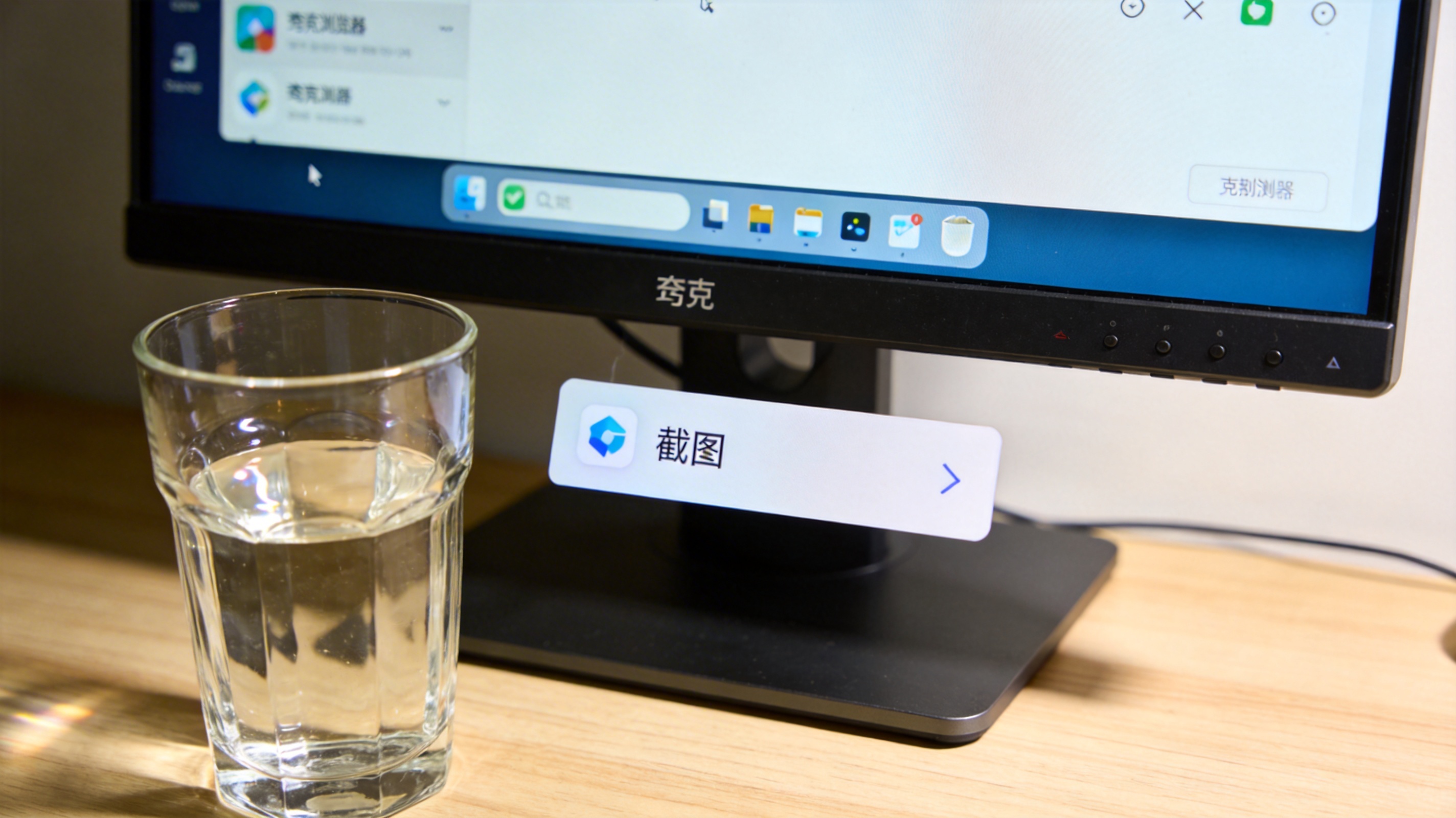 电脑桌面的显示器，屏幕显示夸克浏览器界面，底部弹出含截图选项的菜单，旁边放着玻璃水杯，室内自然光