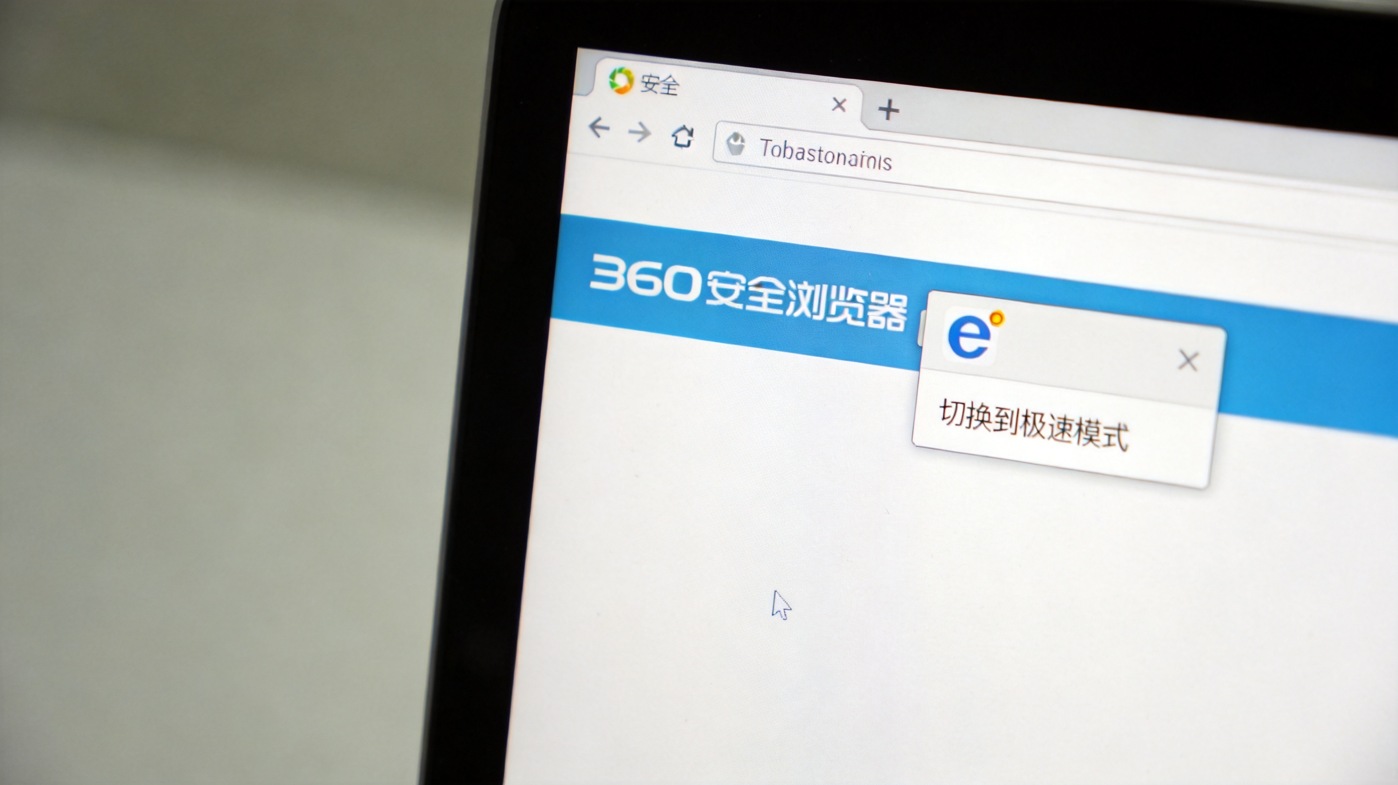 电脑桌面，屏幕显示360安全浏览器页面，地址栏右侧显示“e”图标，旁边弹出切换到极速模式的菜单，室内自然光