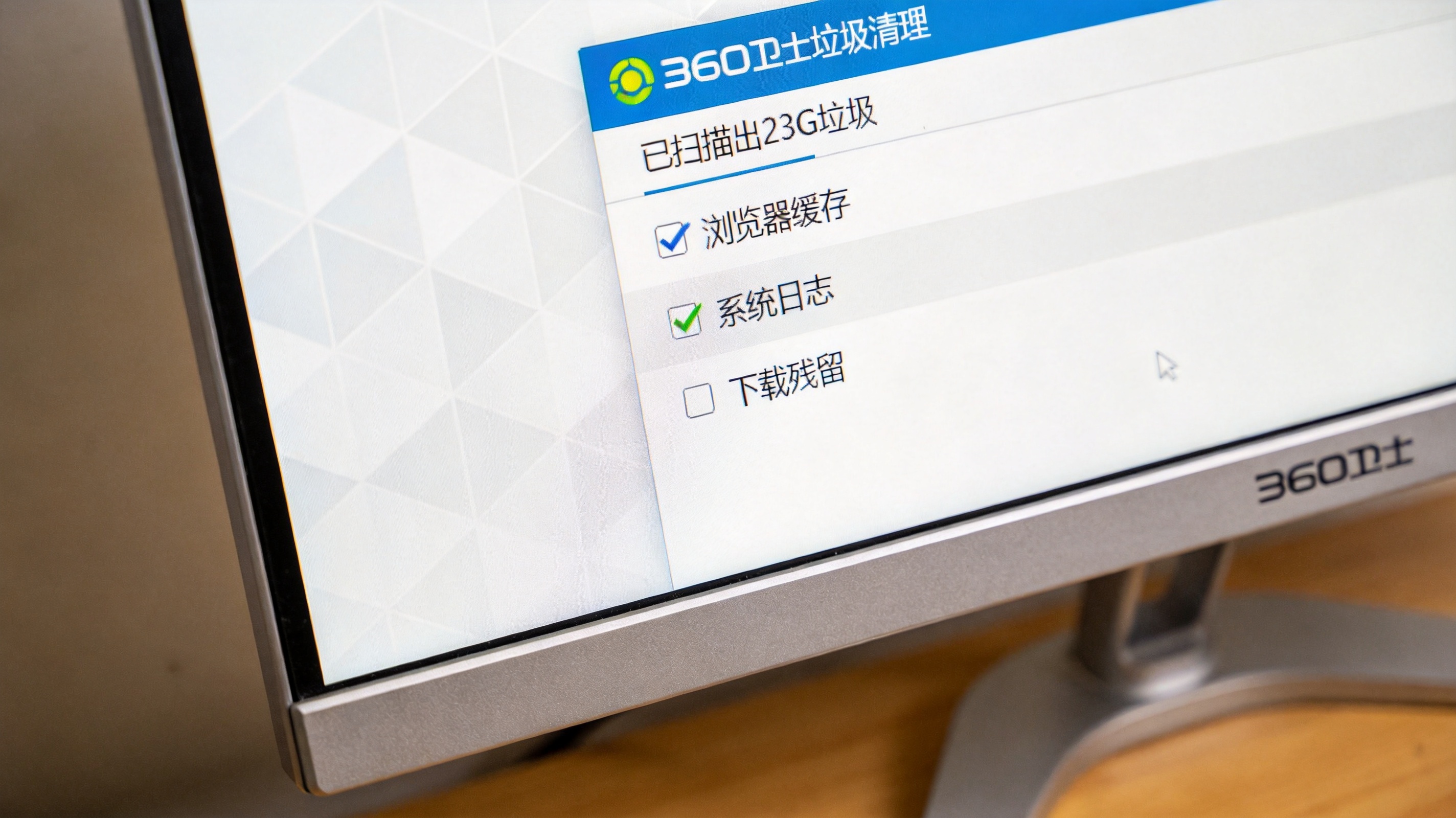 电脑桌面，屏幕显示360卫士垃圾清理界面，已扫描出23G垃圾，选项栏勾选浏览器缓存、系统日志、下载残留，室内自然光