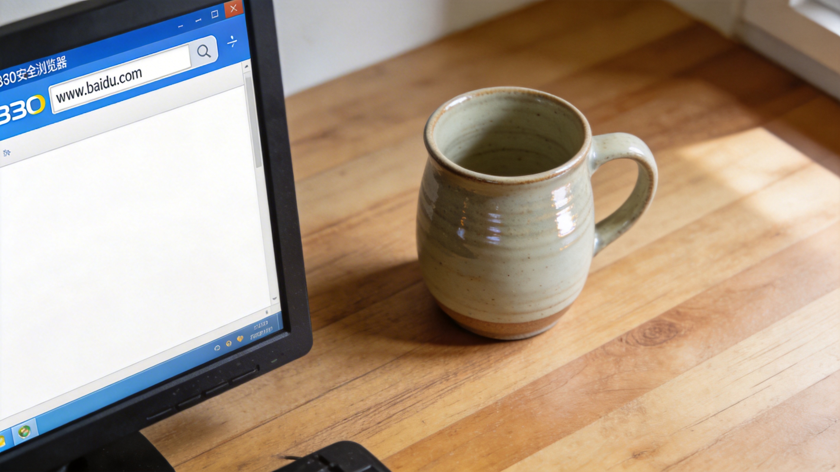 电脑桌面，屏幕显示360安全浏览器界面，地址栏输入着www.baidu.com，旁边放着陶瓷水杯，室内自然光