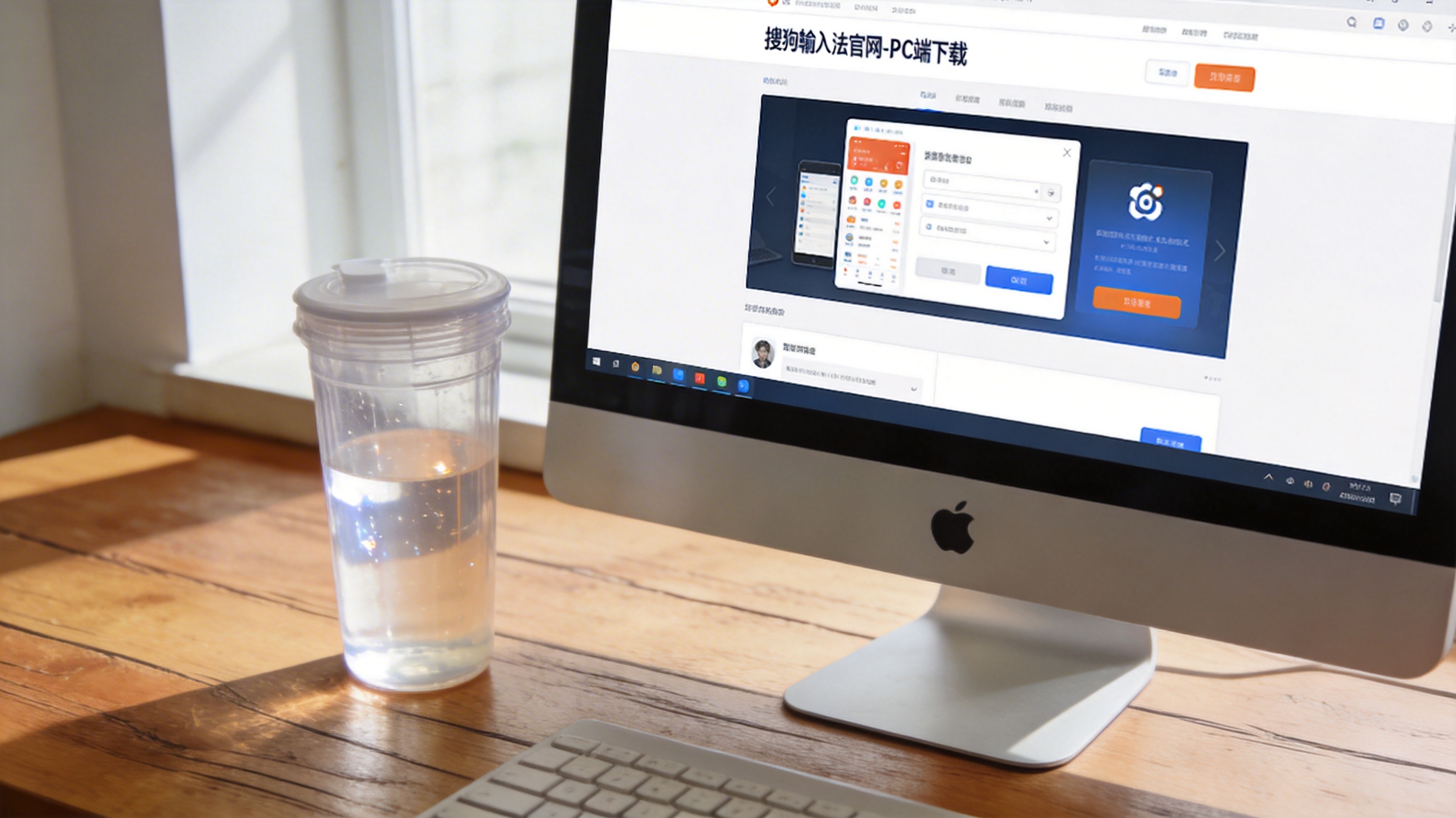 电脑桌的Windows系统电脑，屏幕显示搜狗输入法官网的PC端下载页面，旁边放着半透明塑料水杯，室内自然光
