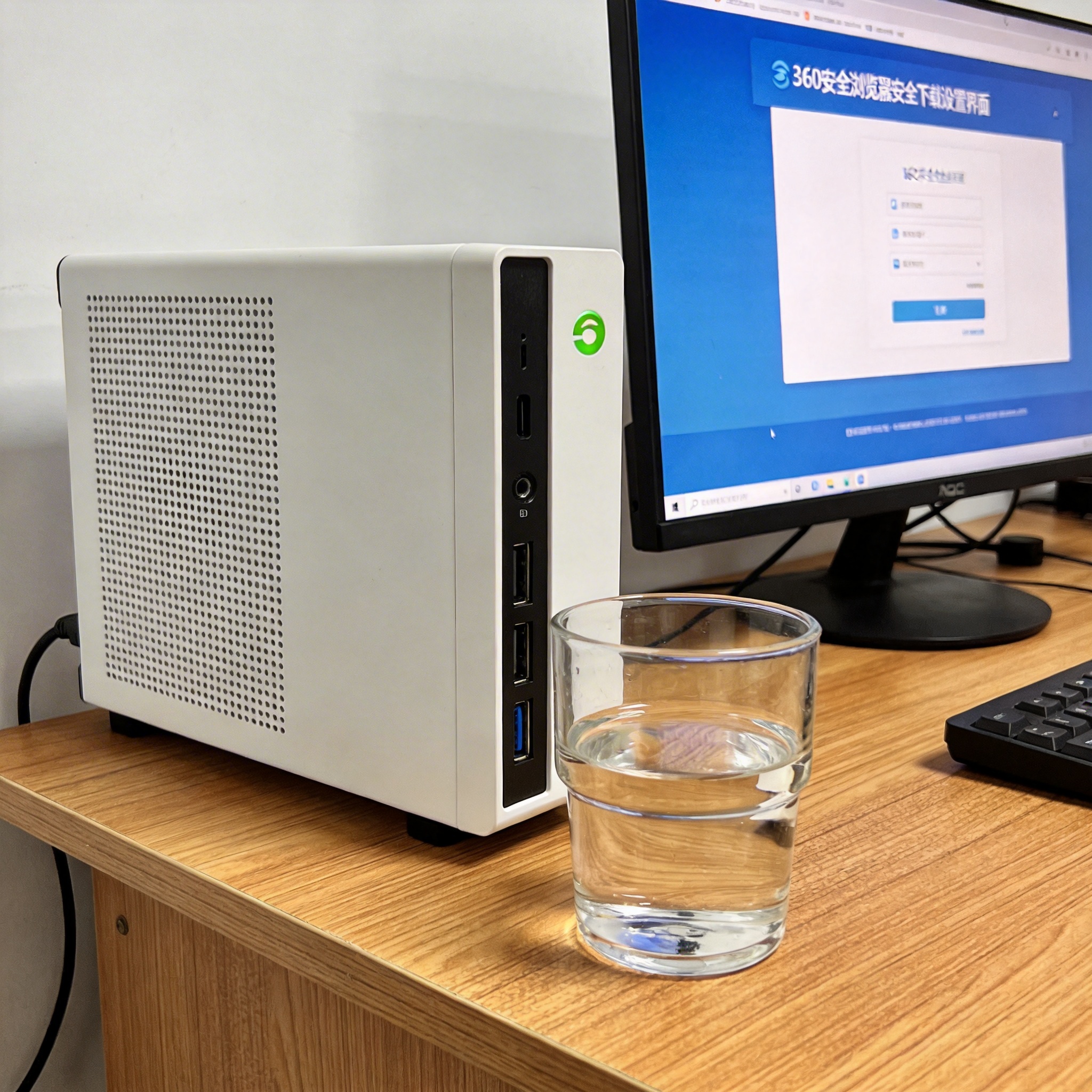 书桌上的主机，屏幕显示360 安全浏览器安全下载设置界面，桌角放着水杯，自然光