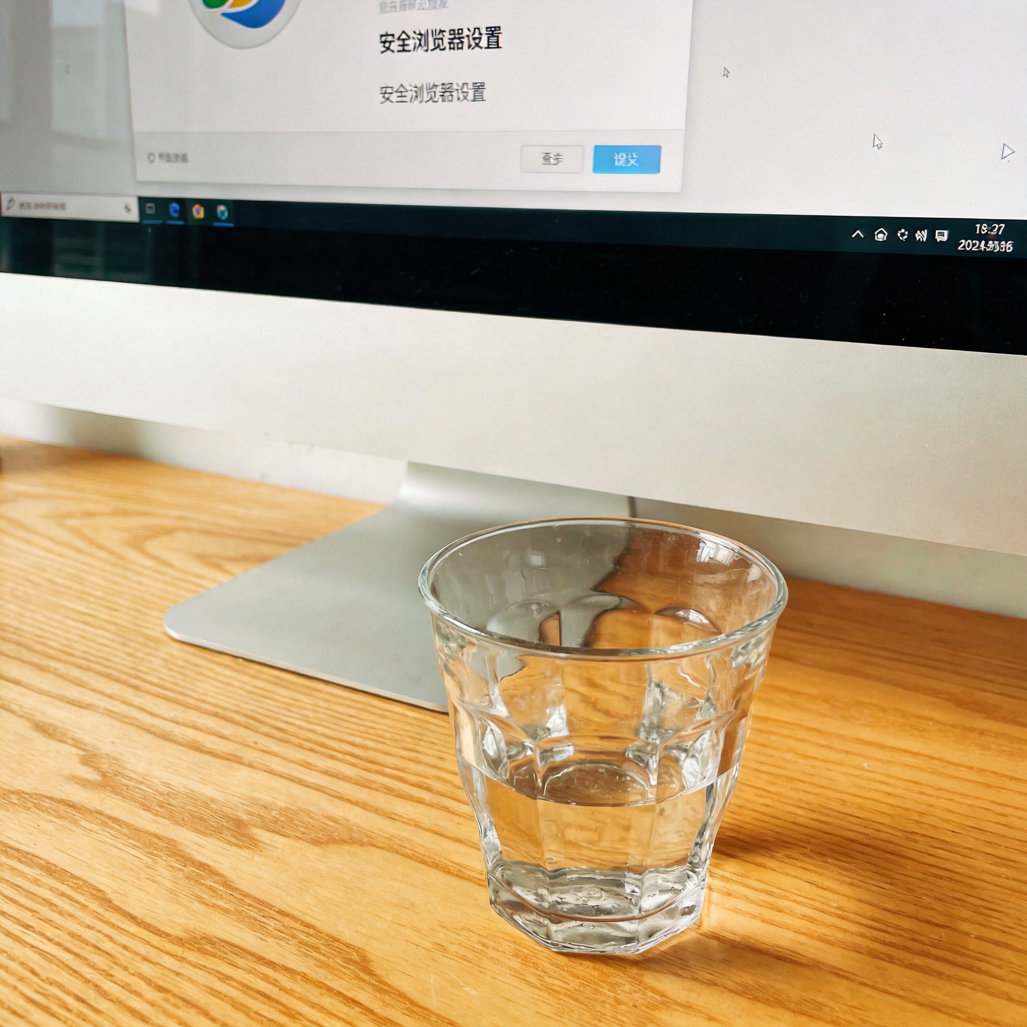 书桌上的电脑，屏幕显示安全浏览器设置界面，桌角放着水杯，自然光