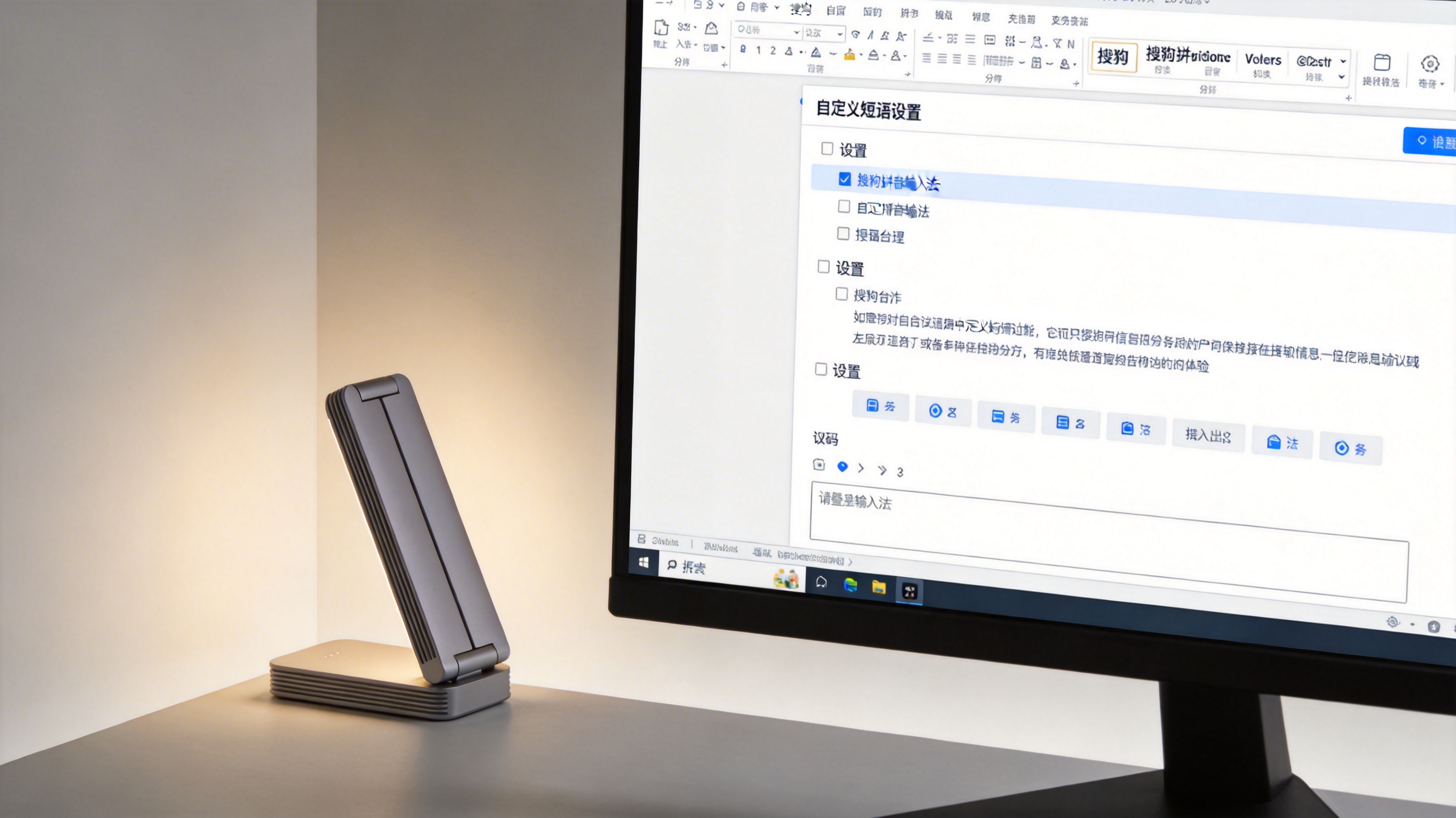 台式机电脑屏幕，显示搜狗拼音输入法的自定义短语设置界面，下方有输入框，桌面角落摆着折叠台灯，屏幕光为主照明