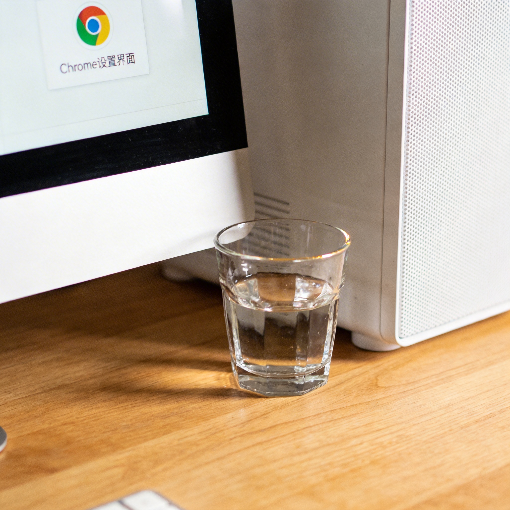 书桌上的主机，屏幕显示Chrome设置界面，桌角放着水杯，自然光
