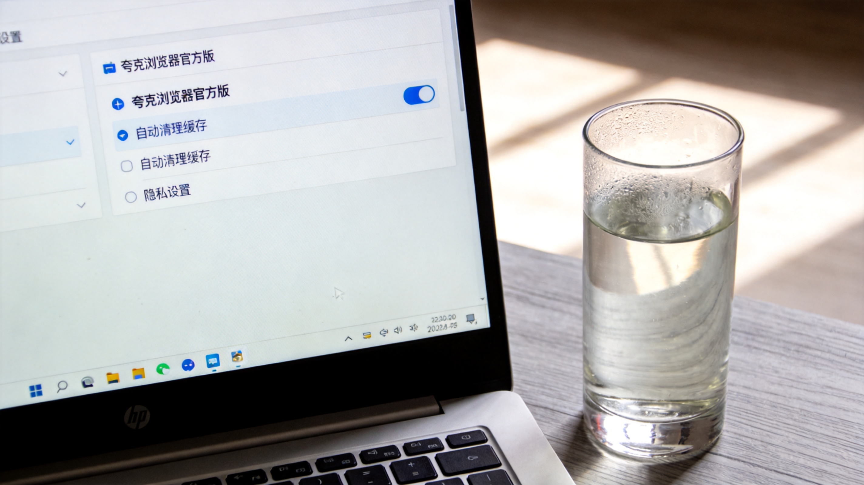 电脑桌面，屏幕显示夸克浏览器官方版的隐私设置界面，自动清理缓存选项处于开启状态，桌面放着半杯温水，室内自然光