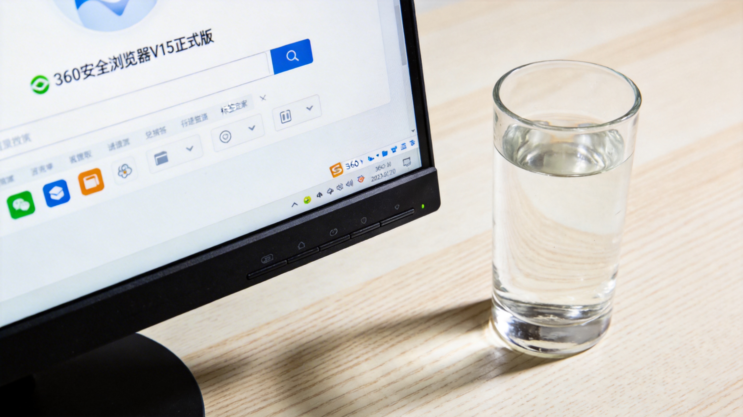 电脑桌面，屏幕显示360安全浏览器V15正式版界面，旁边放着半杯温水，室内自然光