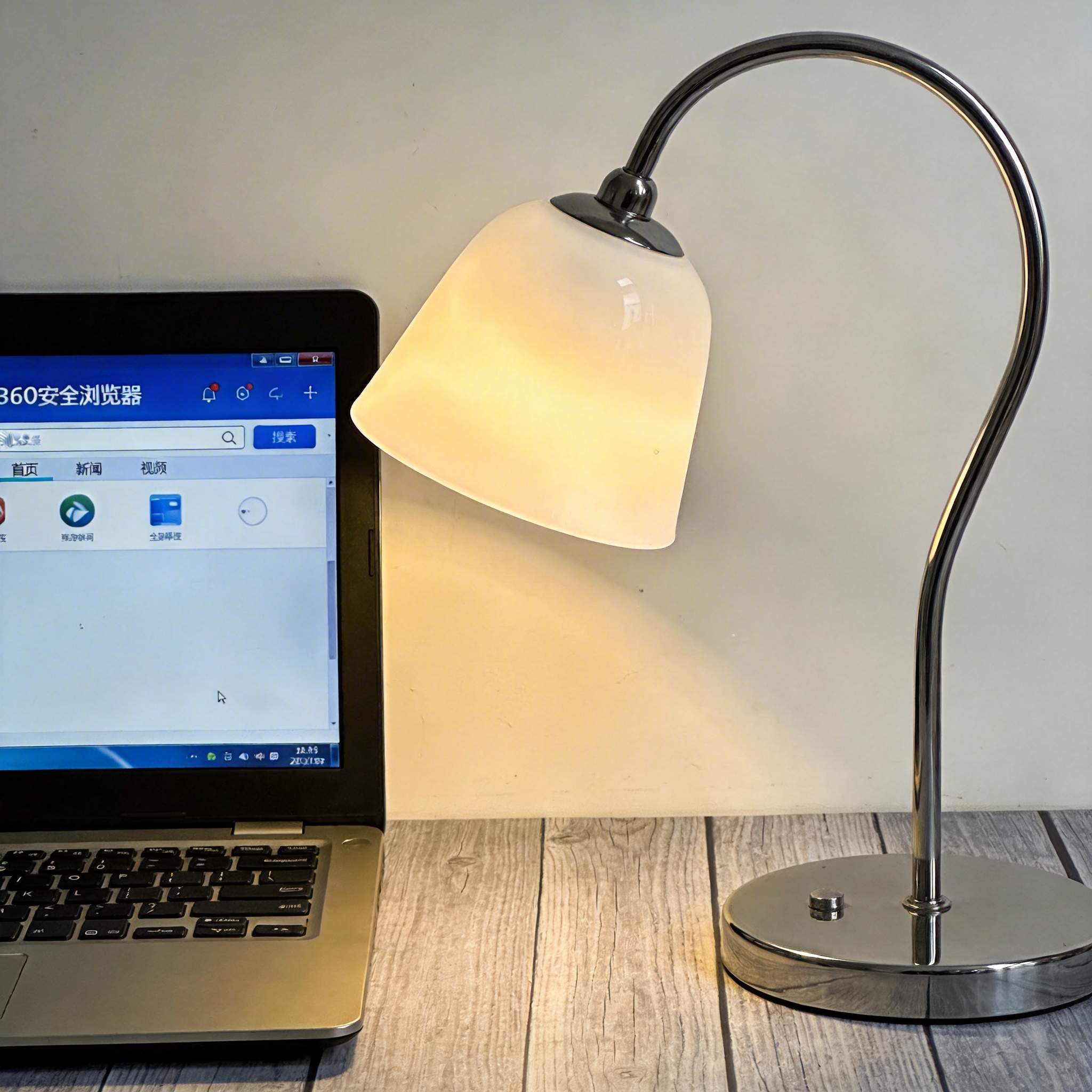 电脑桌上的电脑，屏幕显示360安全浏览器界面，旁边放着台灯