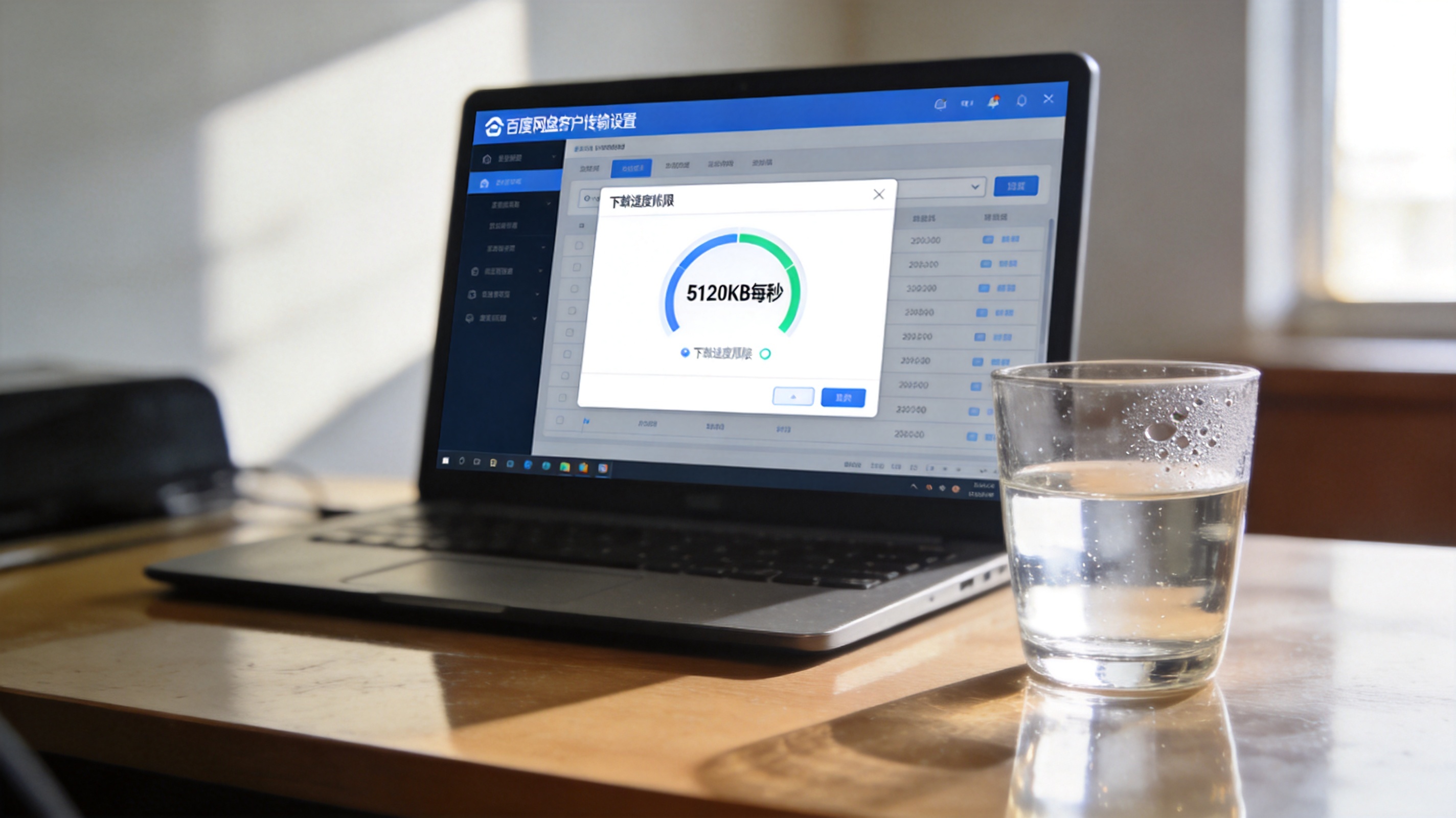 电脑桌面，屏幕显示百度网盘客户端传输设置界面，下载速度上限设为5120KB每秒，旁边放着半杯凉白开，室内自然光