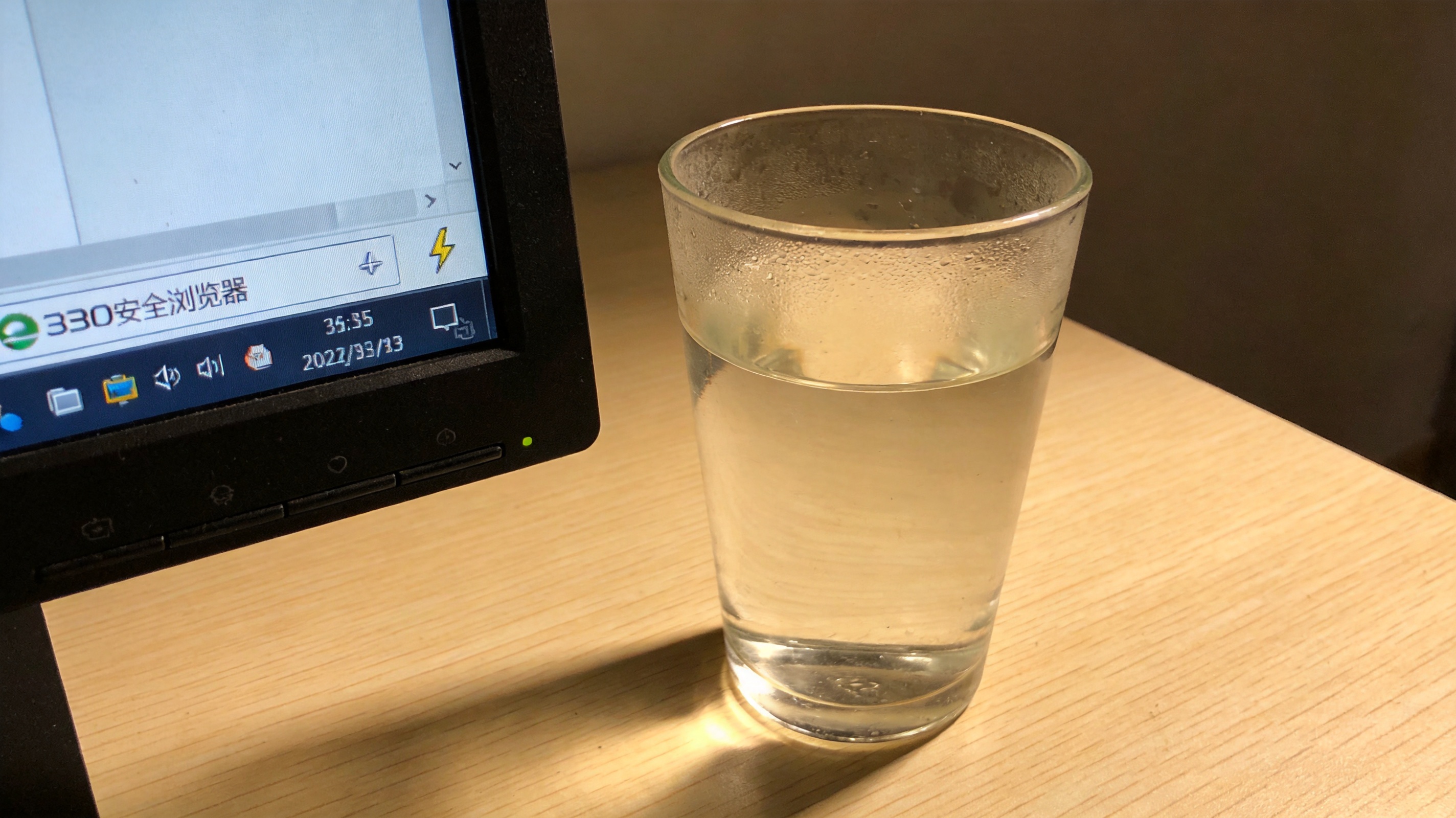 电脑桌面，屏幕显示360安全浏览器界面，地址栏右侧显示闪电图标，旁边放着半杯温水，室内自然光