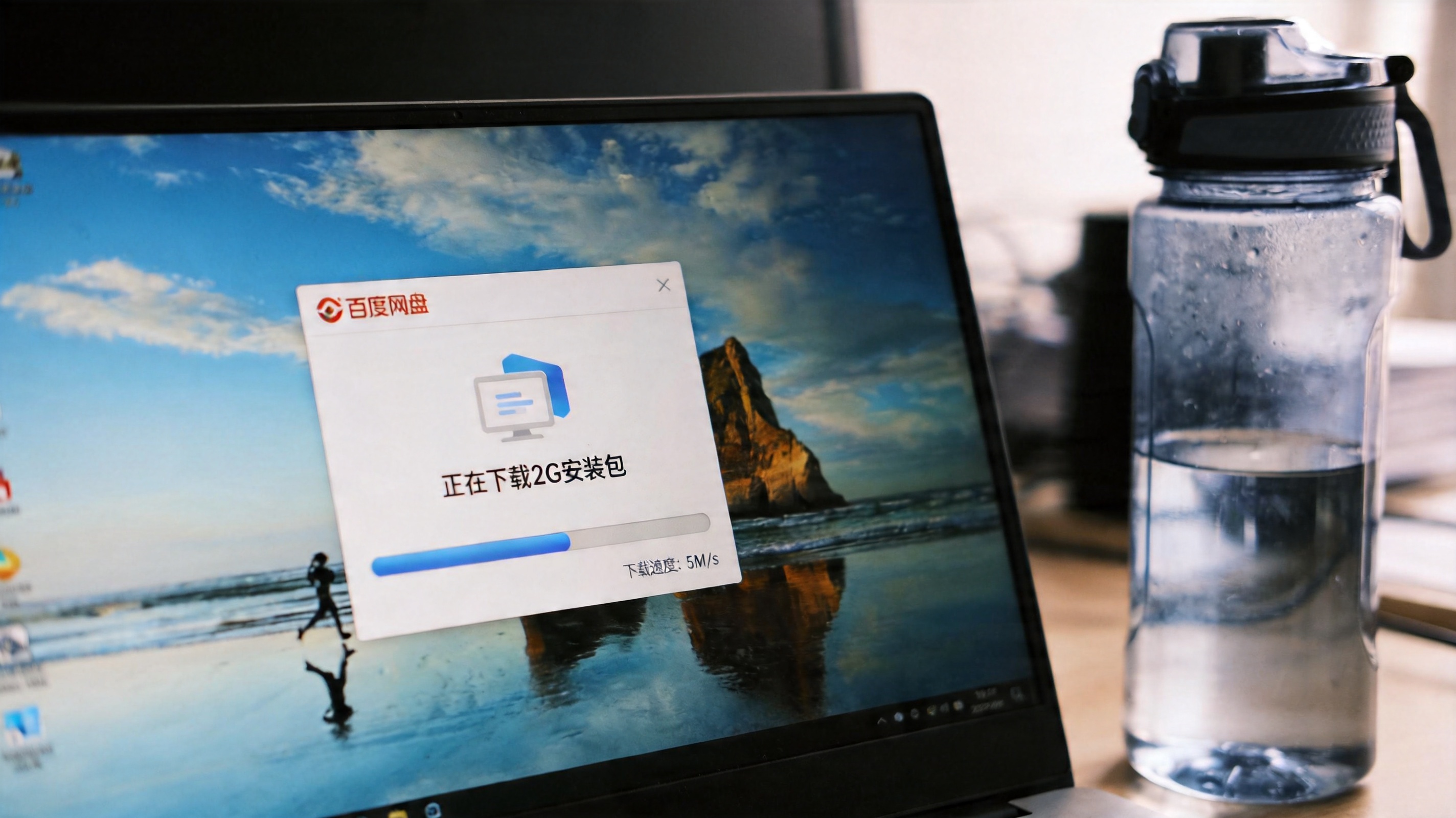 电脑桌面，屏幕显示百度网盘界面，正在下载2G安装包，下载速度显示5M/s，旁边放着半透明塑料水杯，室内自然光