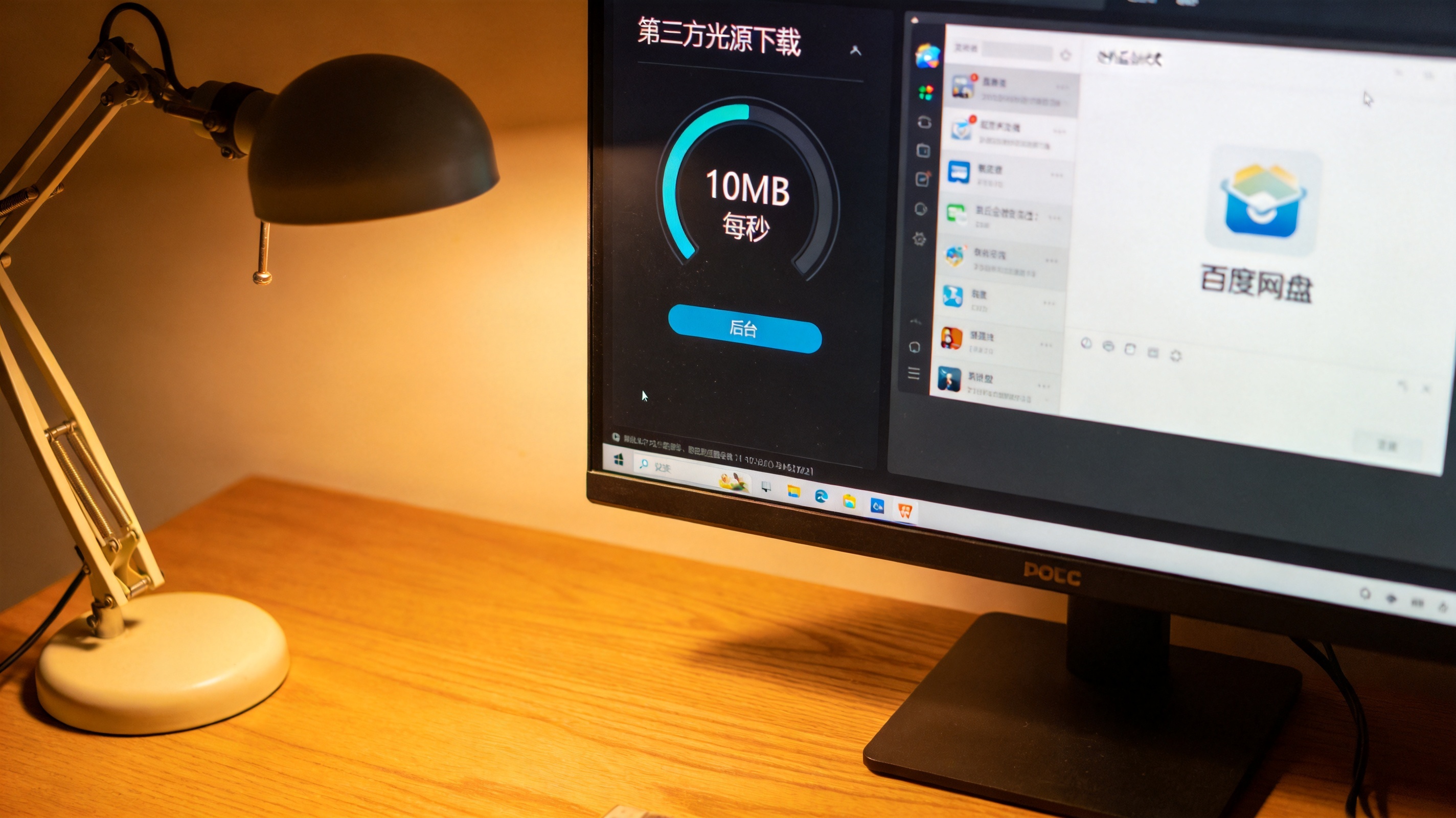 书桌的电脑屏幕显示第三方开源下载工具界面，速度显示10MB每秒，旁边的百度网盘窗口处于后台状态，台灯暖光