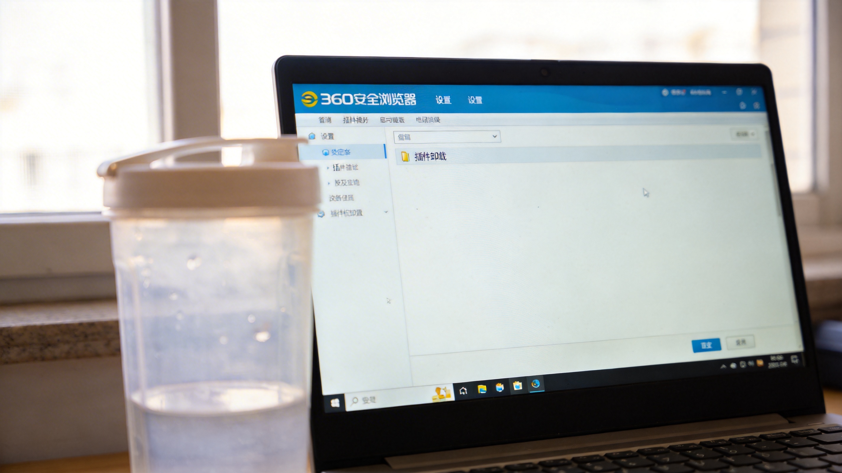 电脑桌面，屏幕显示360安全浏览器的设置页面，界面上有插件卸载选项，旁边放着半透明塑料水杯，室内自然光